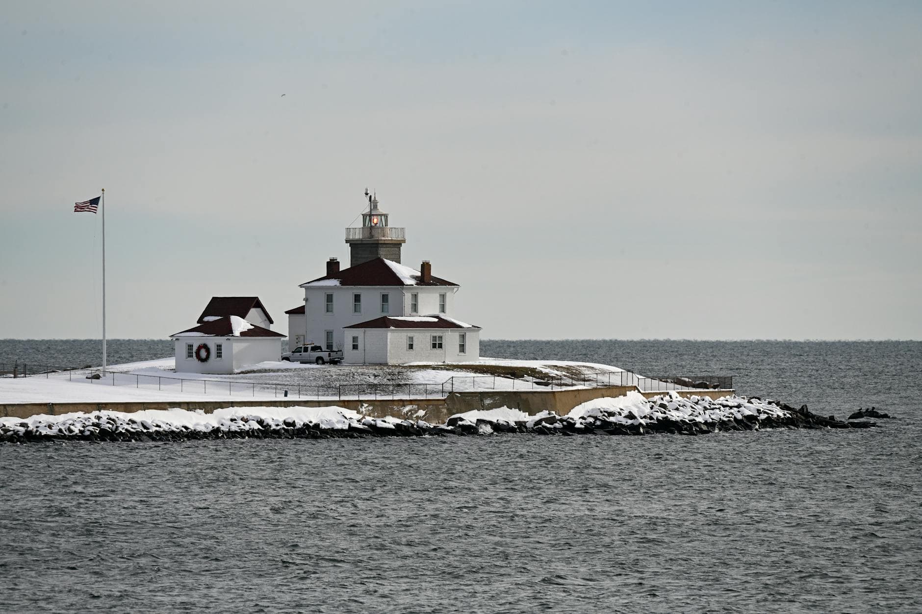A scenic view of a lighthouse on a snowy coast in Westerly, Rhode Island, USA.