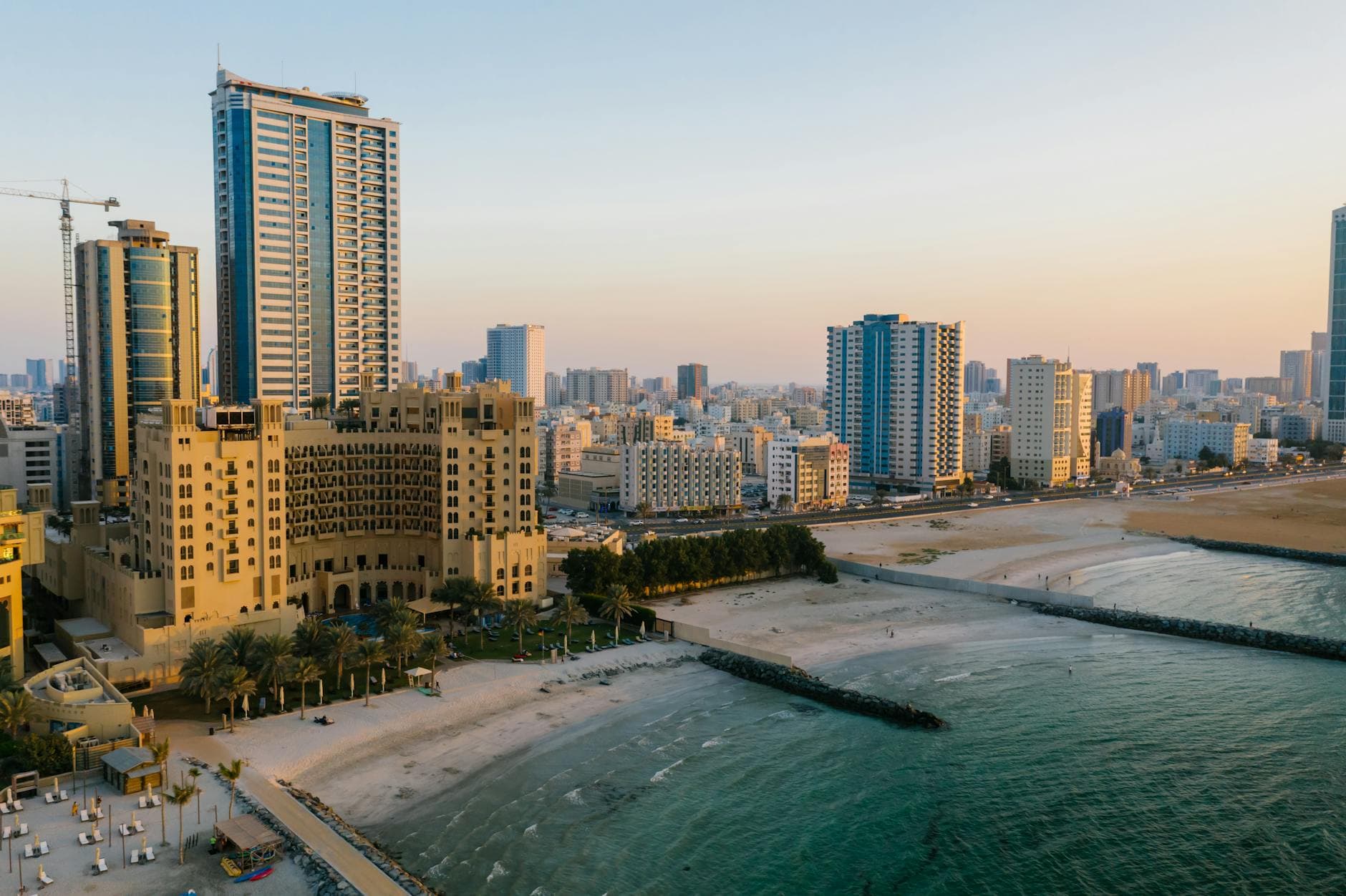 Explore the stunning aerial view of Ajman's urban coastal landscape, captured at sunset.