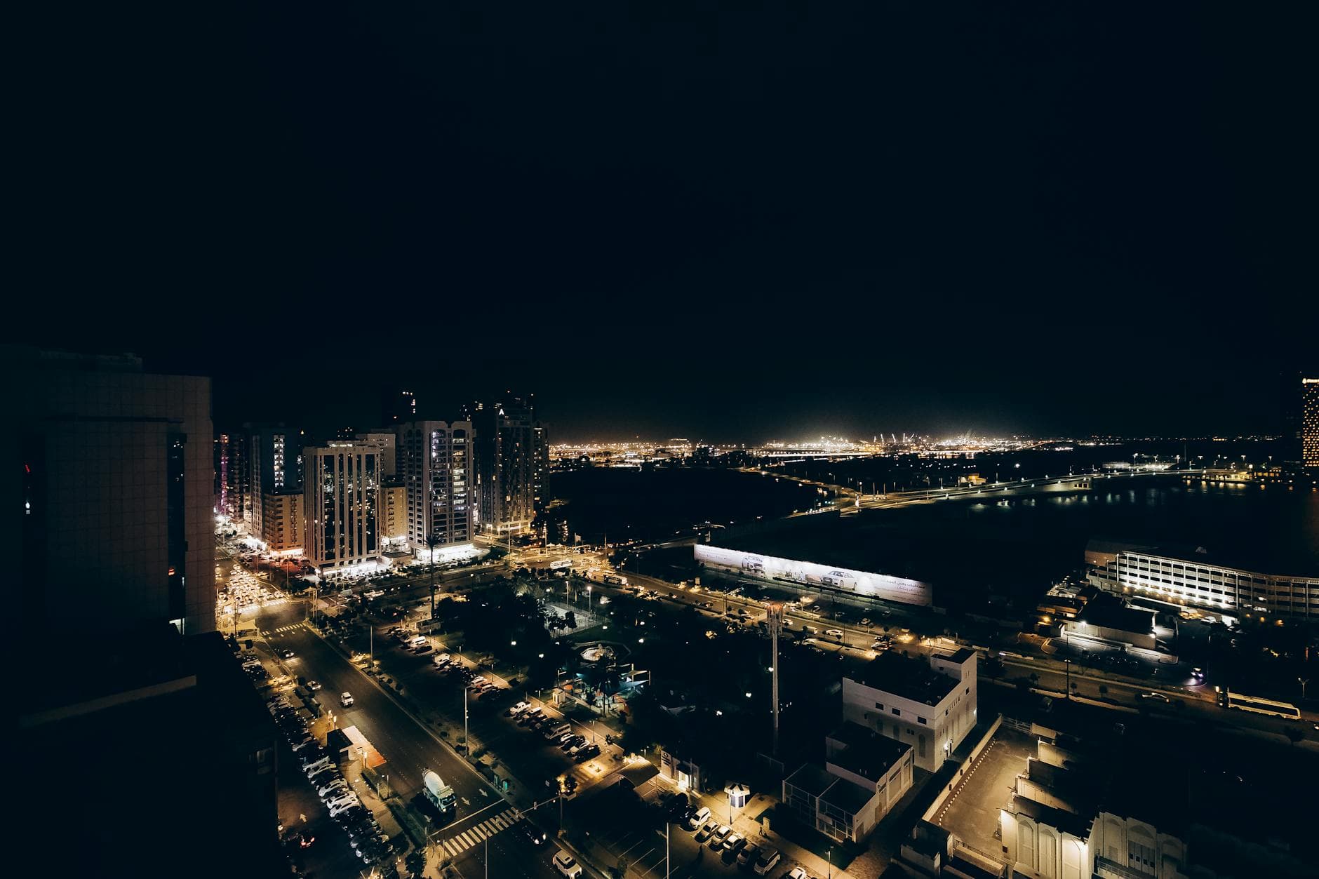A stunning aerial view of Abu Dhabi at night showcasing illuminated streets and buildings.