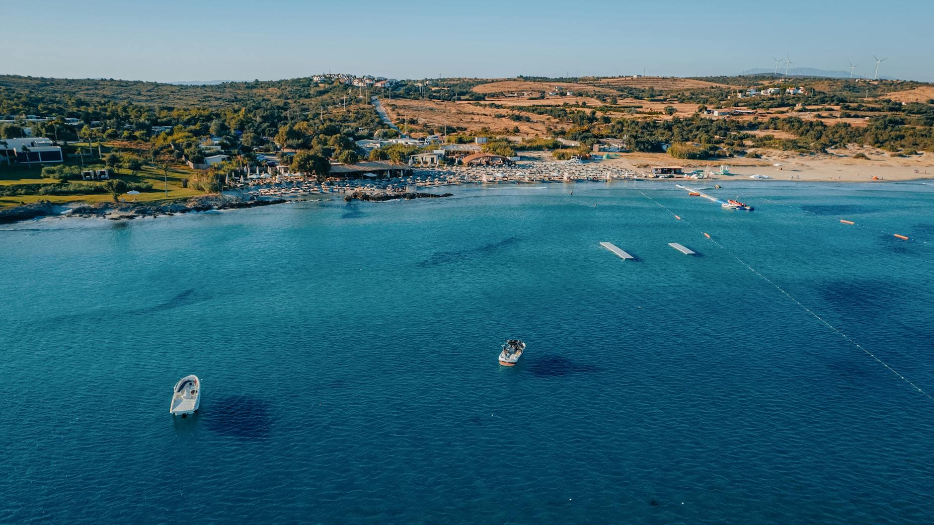 Captivating aerial shot of Alaçatı's beautiful coastline with boats and turquoise waters, perfect for travel inspiration.