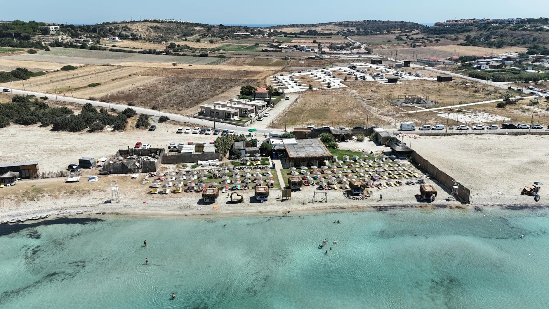 Stunning aerial shot of Alaçatı beach with sun loungers and crystal-clear water in İzmir, Türkiye.