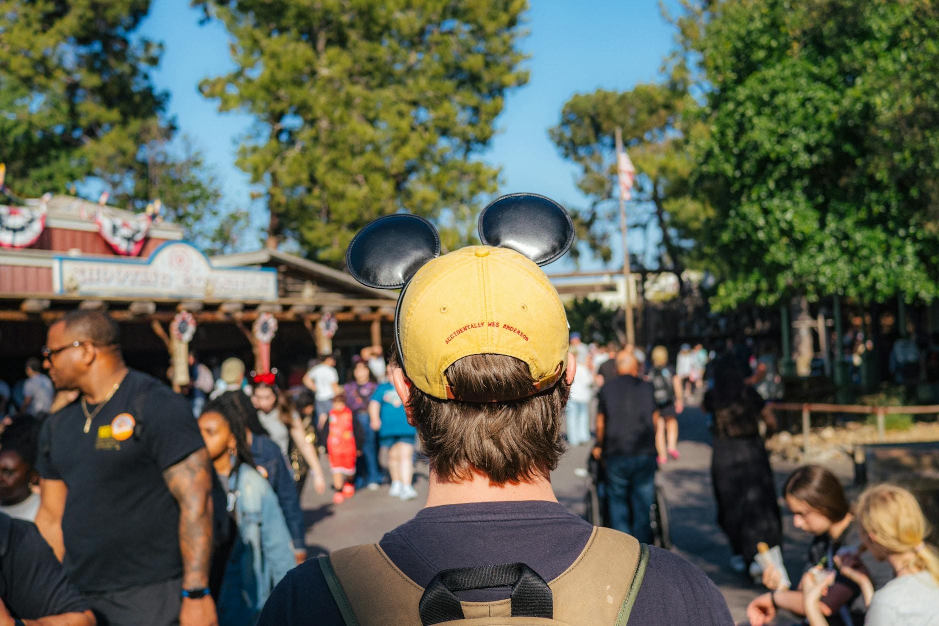 Visitor wearing Mickey ears explores a sunny Disneyland park in Anaheim, California.