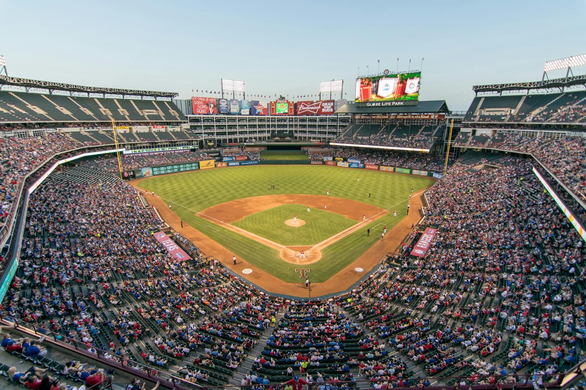 Aerial view of a lively baseball game at the iconic Globe Life Park filled with cheering fans.
