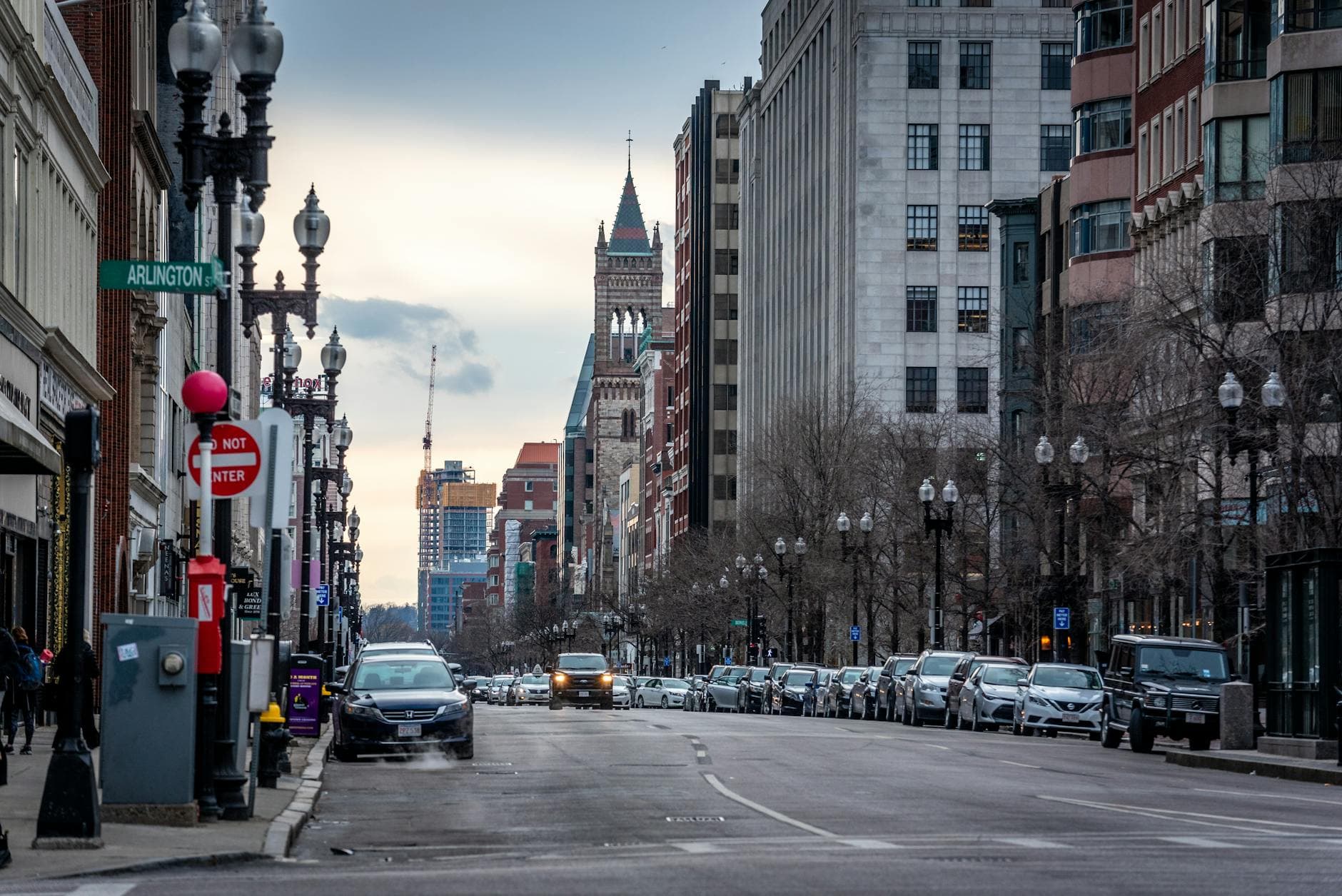 A busy street view in downtown Boston, Massachusetts during dusk showcasing urban architecture and traffic flow.