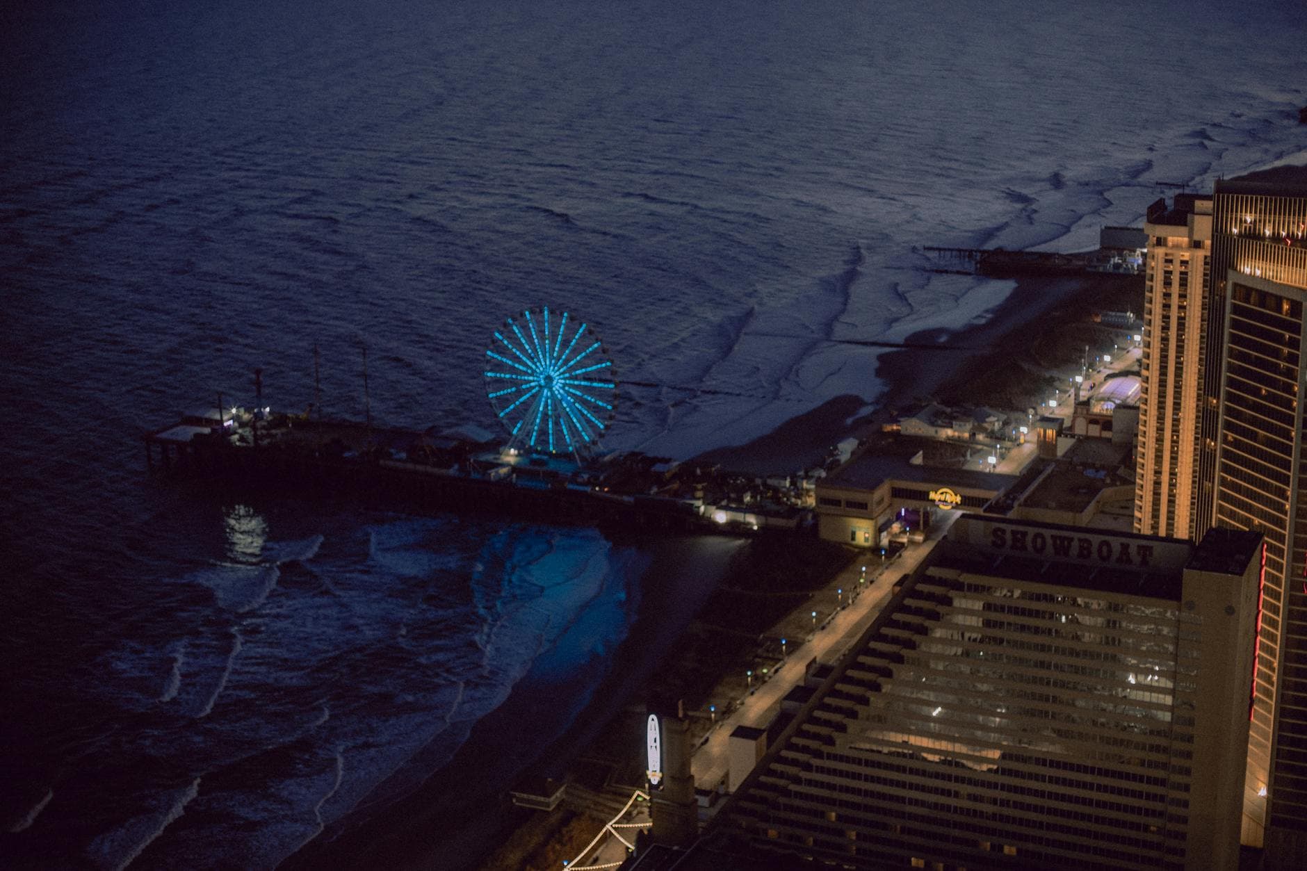 Stunning aerial view of Atlantic City at night featuring an illuminated Ferris wheel by the coast.