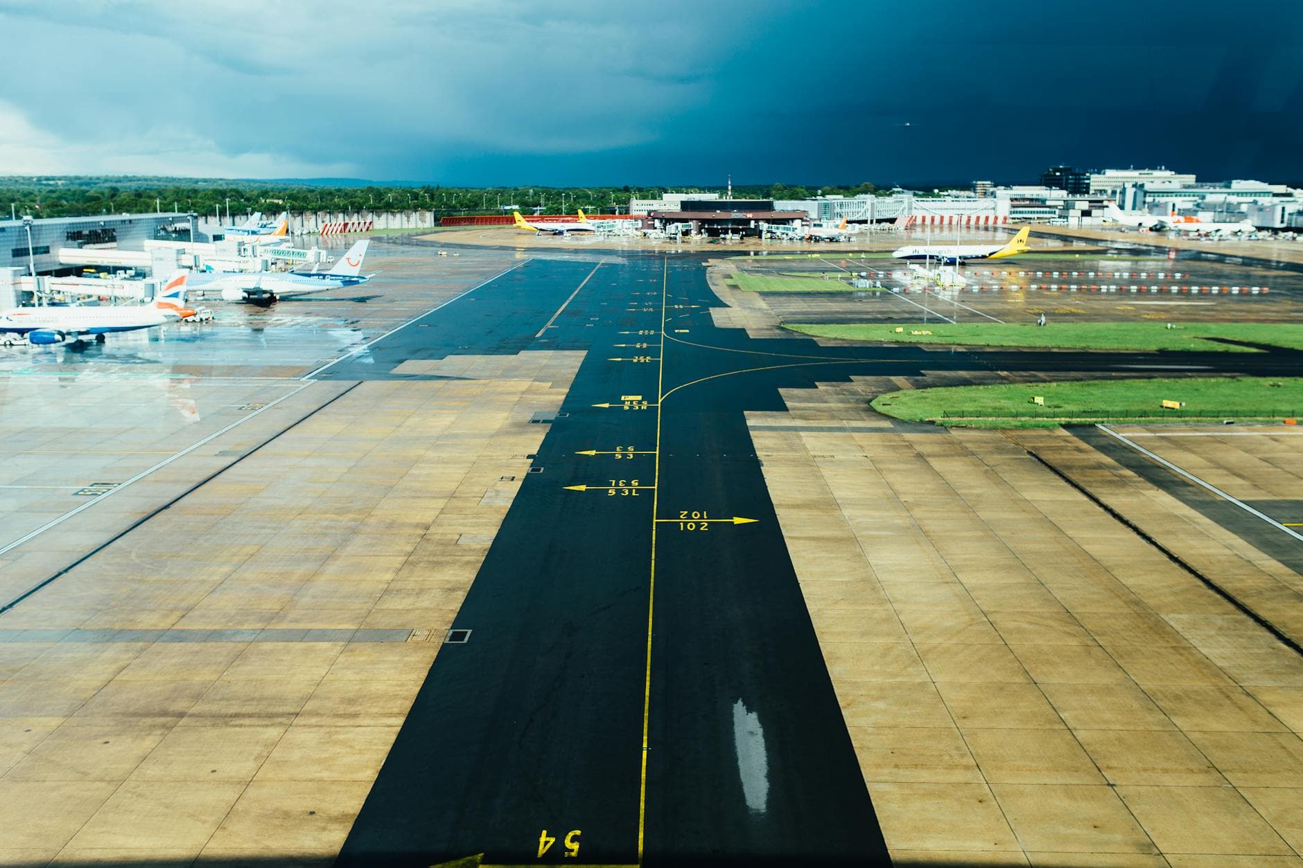 Aerial view of an airport runway with several parked planes on a cloudy day. Ideal for travel and aviation themes.