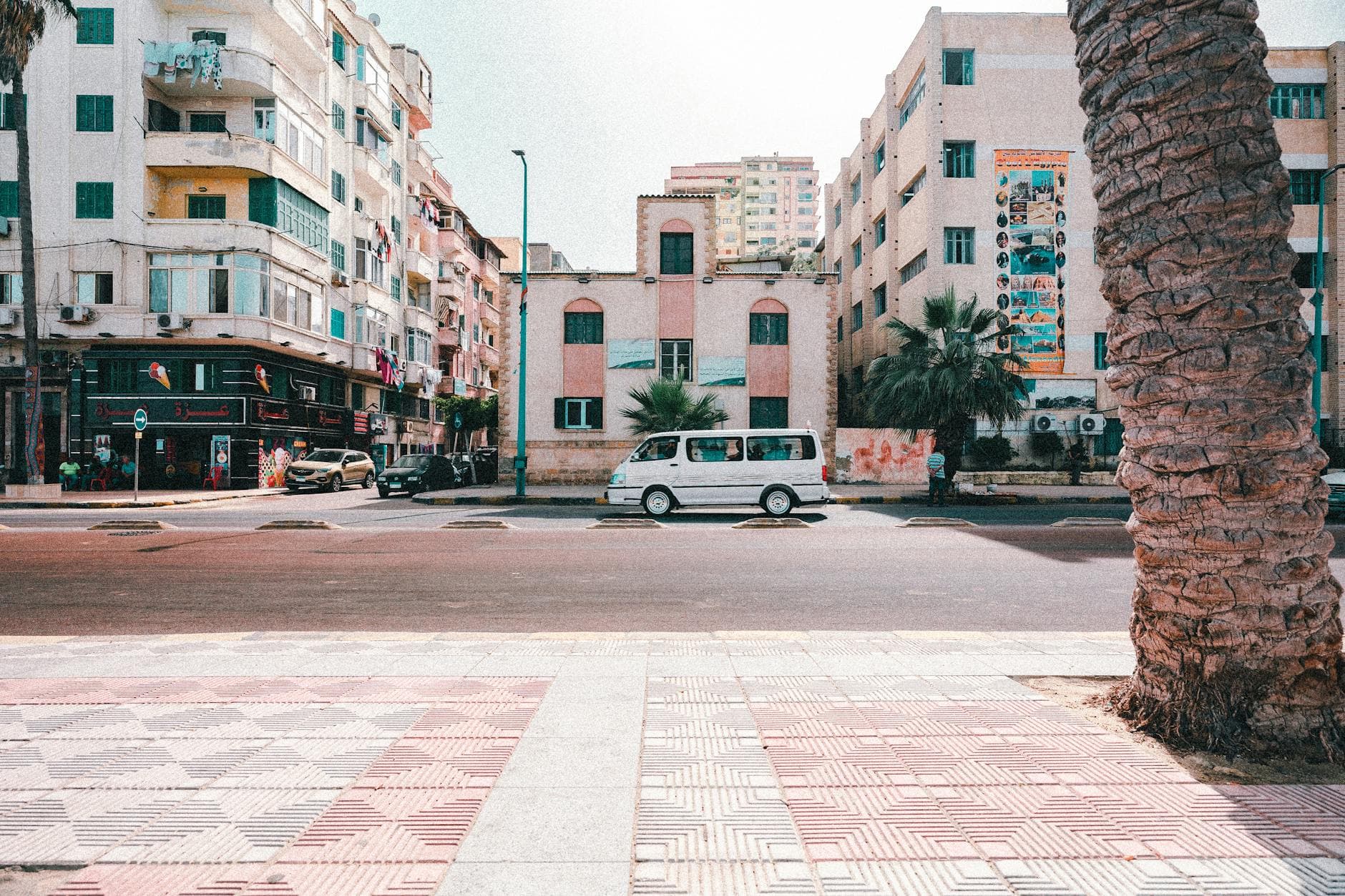 Street view of downtown Alexandria with vehicles and buildings under bright daylight.