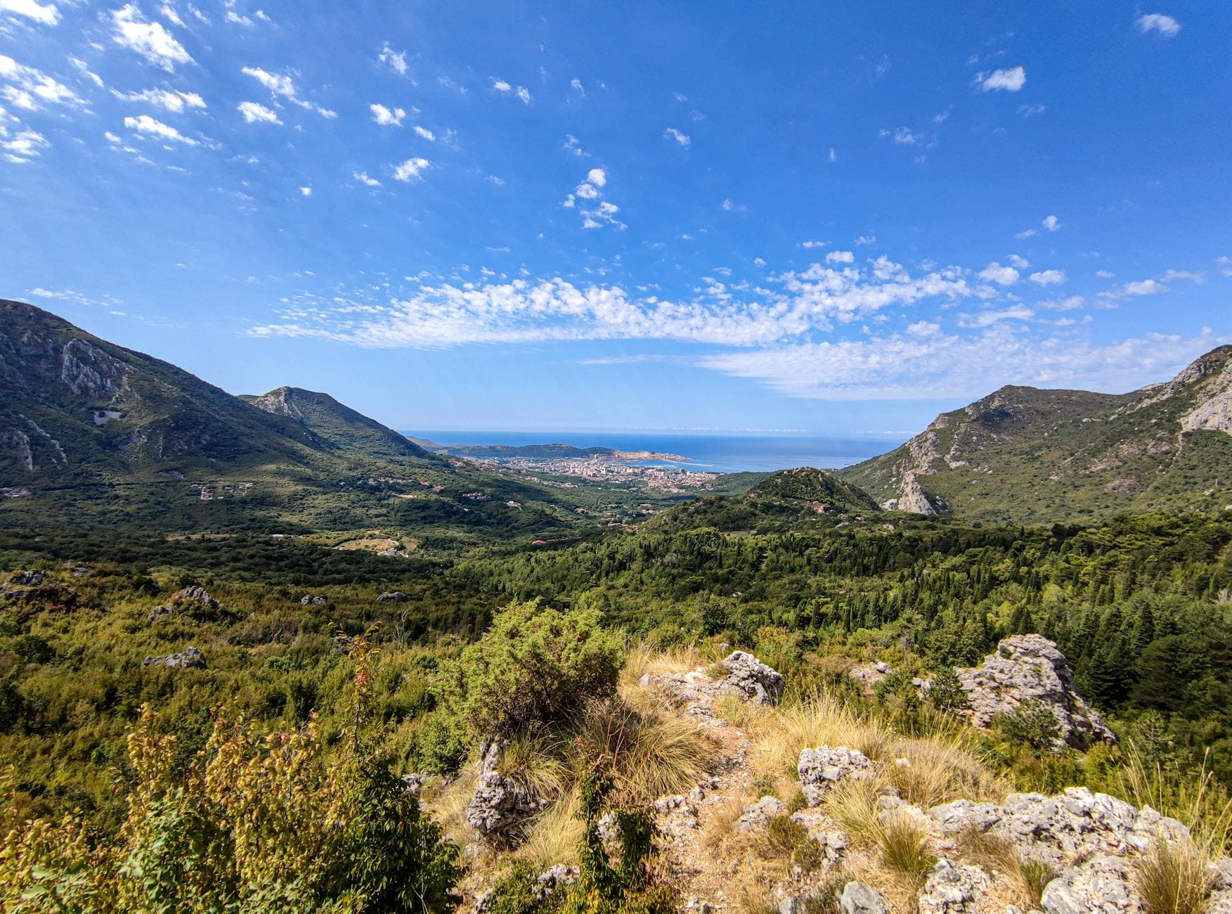A breathtaking panoramic view of the mountains and coastline in Bar, Montenegro under a clear blue sky.