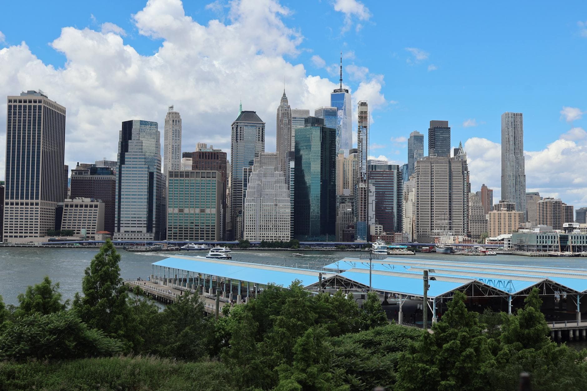 Dramatic view of Downtown Manhattan skyline from Brooklyn with modern skyscrapers and iconic landmarks.