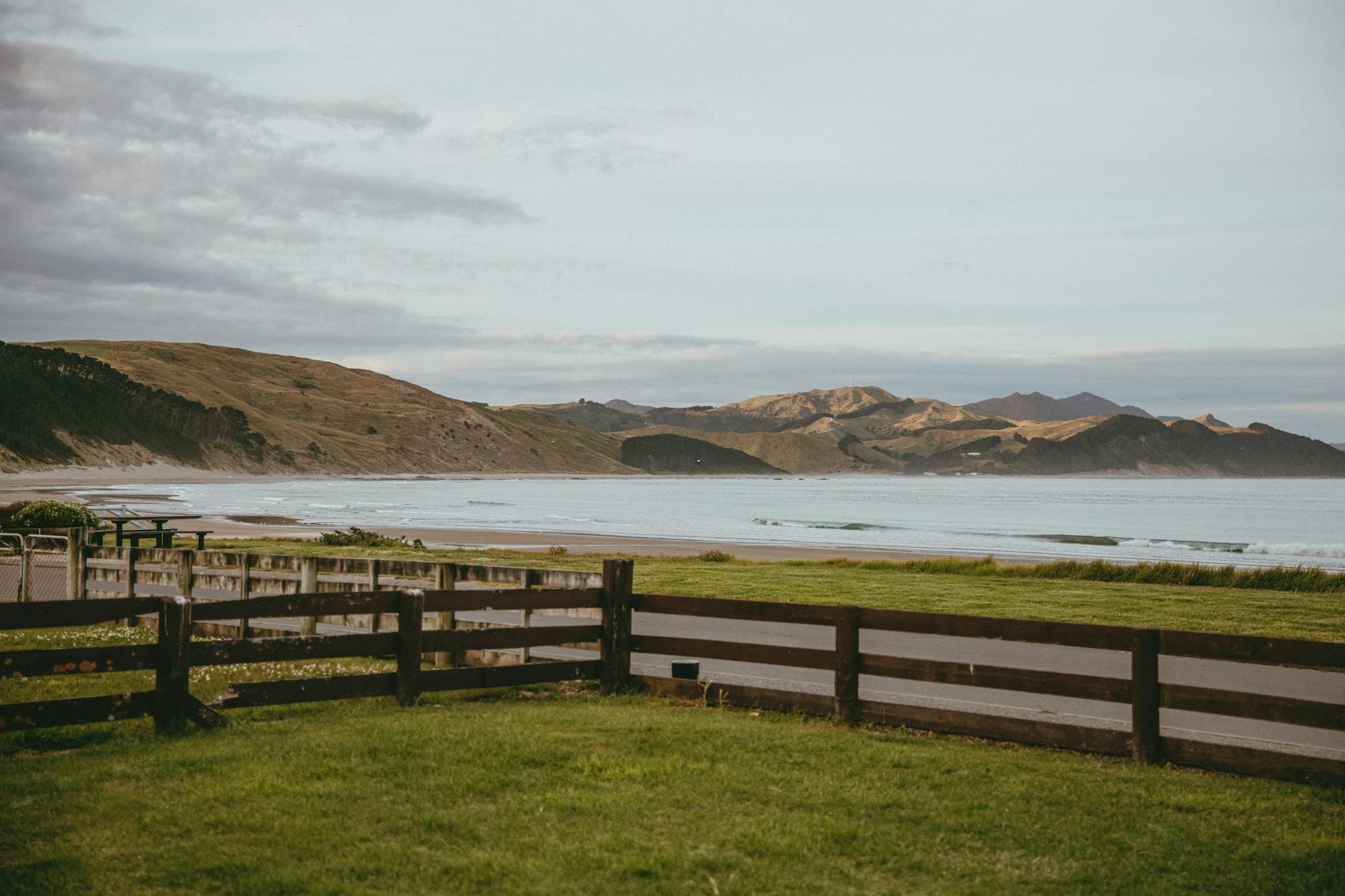 Explore the serene beauty of Castlepoint Beach, New Zealand, featuring rolling hills and gentle waves.