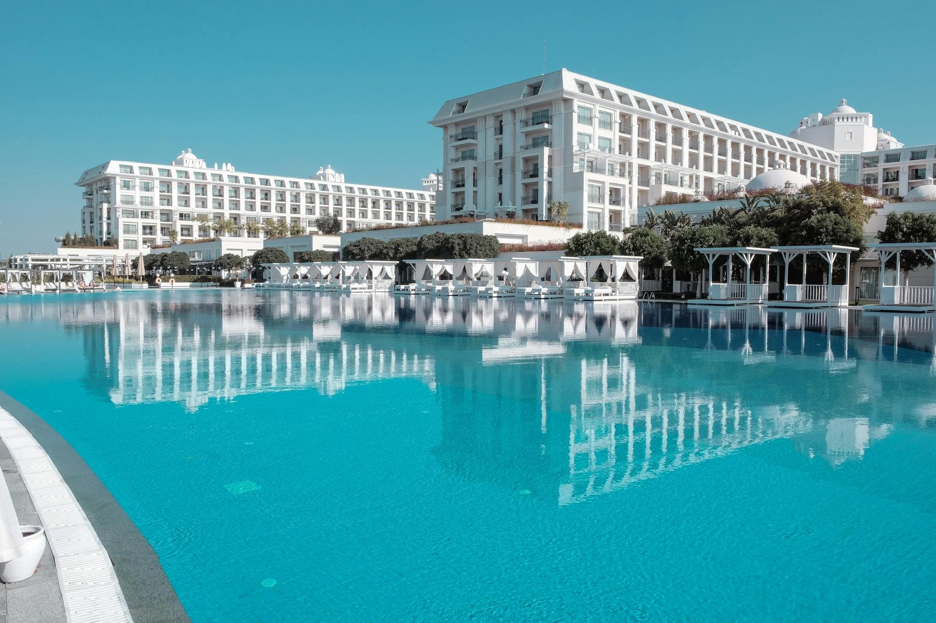 A breathtaking view of a luxurious hotel with a serene swimming pool reflecting the building and sky.