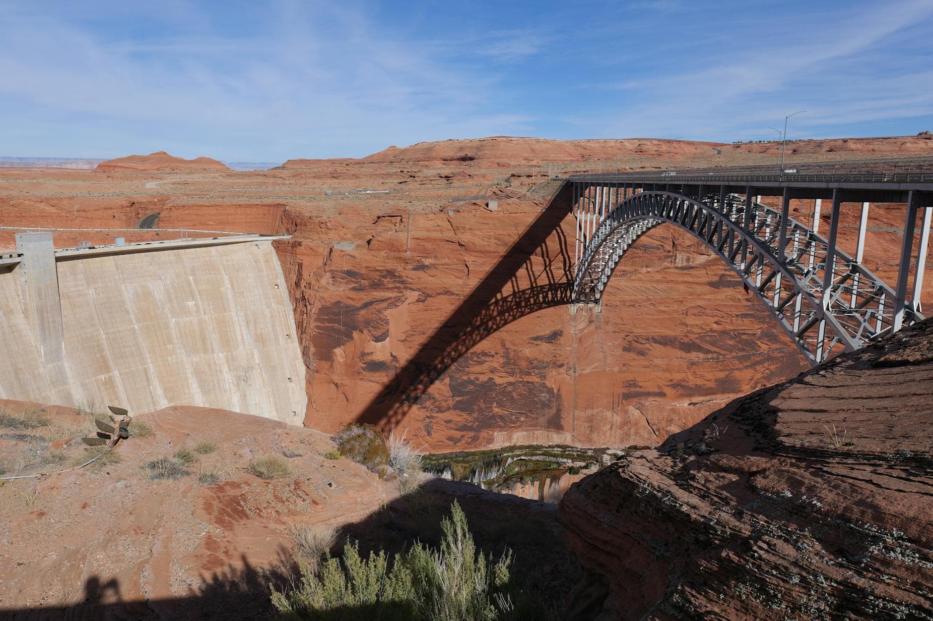 Scenic view of Glen Canyon Dam and steel arch bridge in Arizona's red desert landscape.