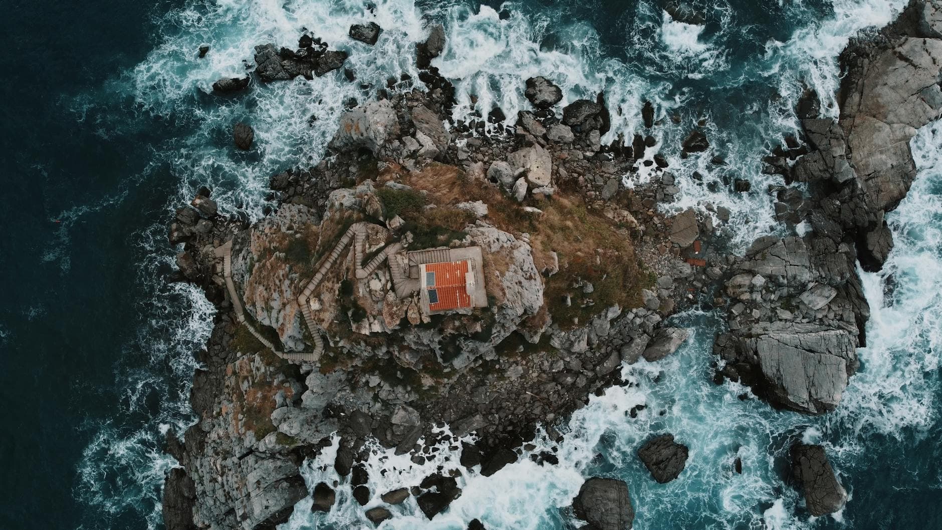 Aerial view of Nedjelja Church on a rocky islet near Petrovac, Montenegro, surrounded by the Adriatic Sea.