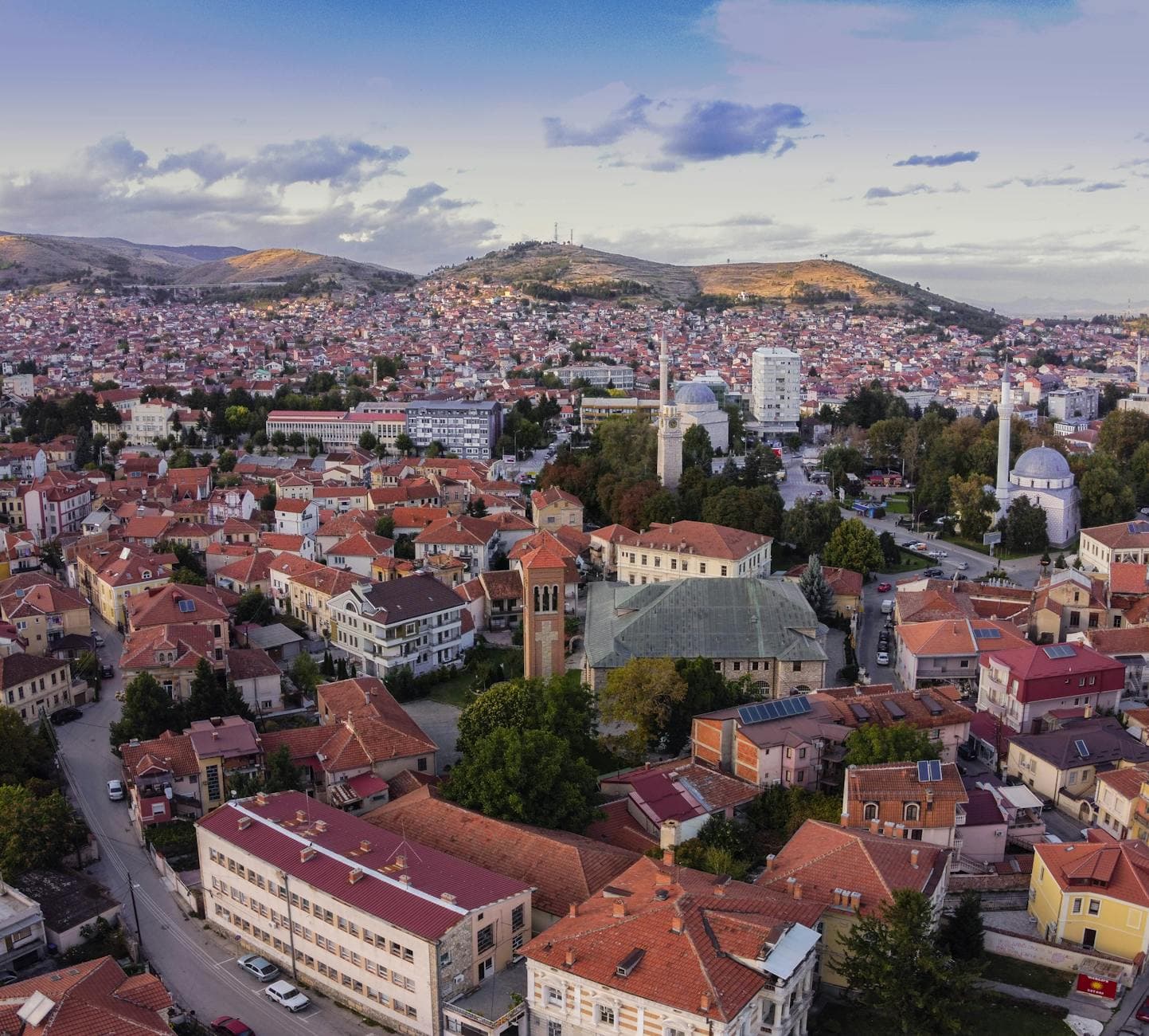 Aerial image showcasing the picturesque townscape of Bitola, North Macedonia, featuring red-roofed buildings and scenic hills.