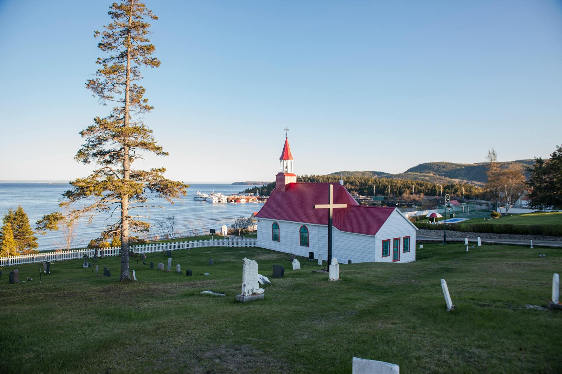 Charming church with a red roof overlooking scenic Tadoussac Bay in Québec, Canada.