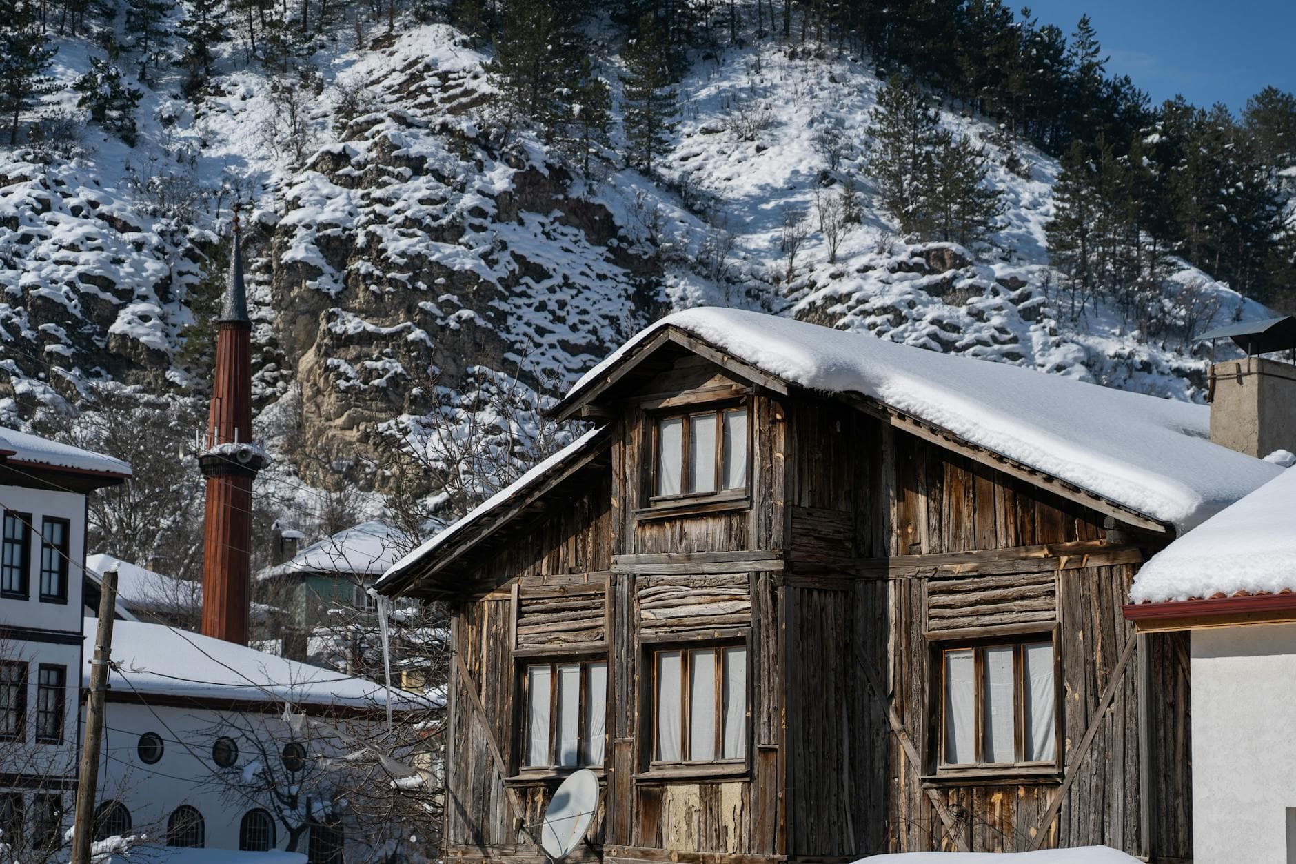 Explore the snow-covered traditional wooden houses and mosque minaret in Mudurnu, Turkey.