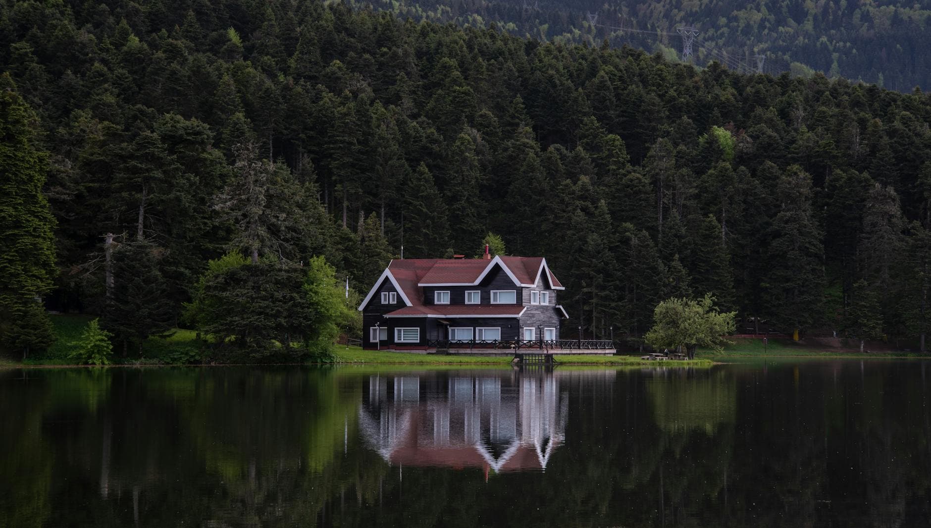Charming lake house surrounded by lush forest in Bolu, Türkiye, with serene water reflections.