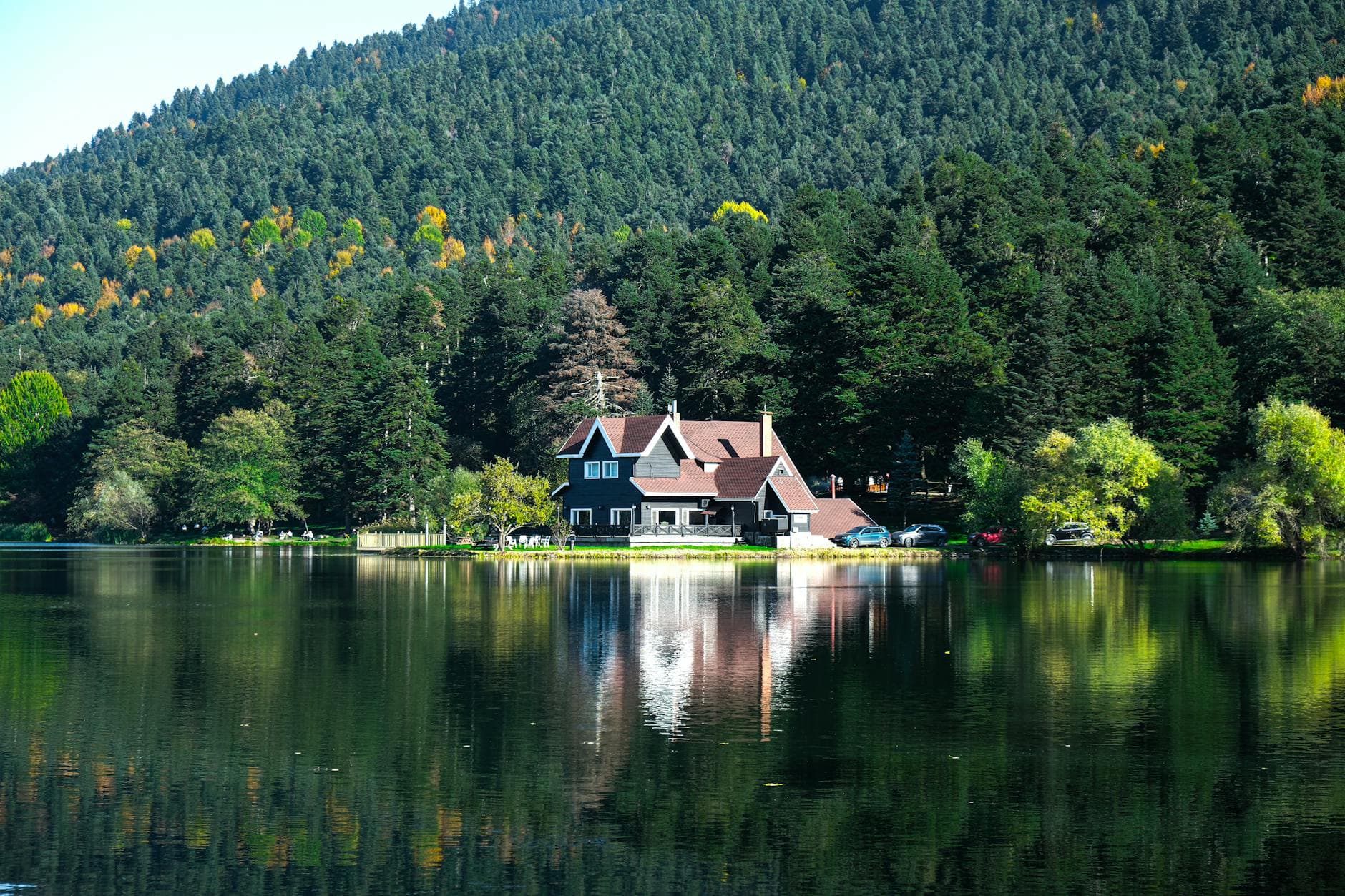 Scenic view of a charming house by a tranquil lake surrounded by lush forest in Bolu, Türkiye.