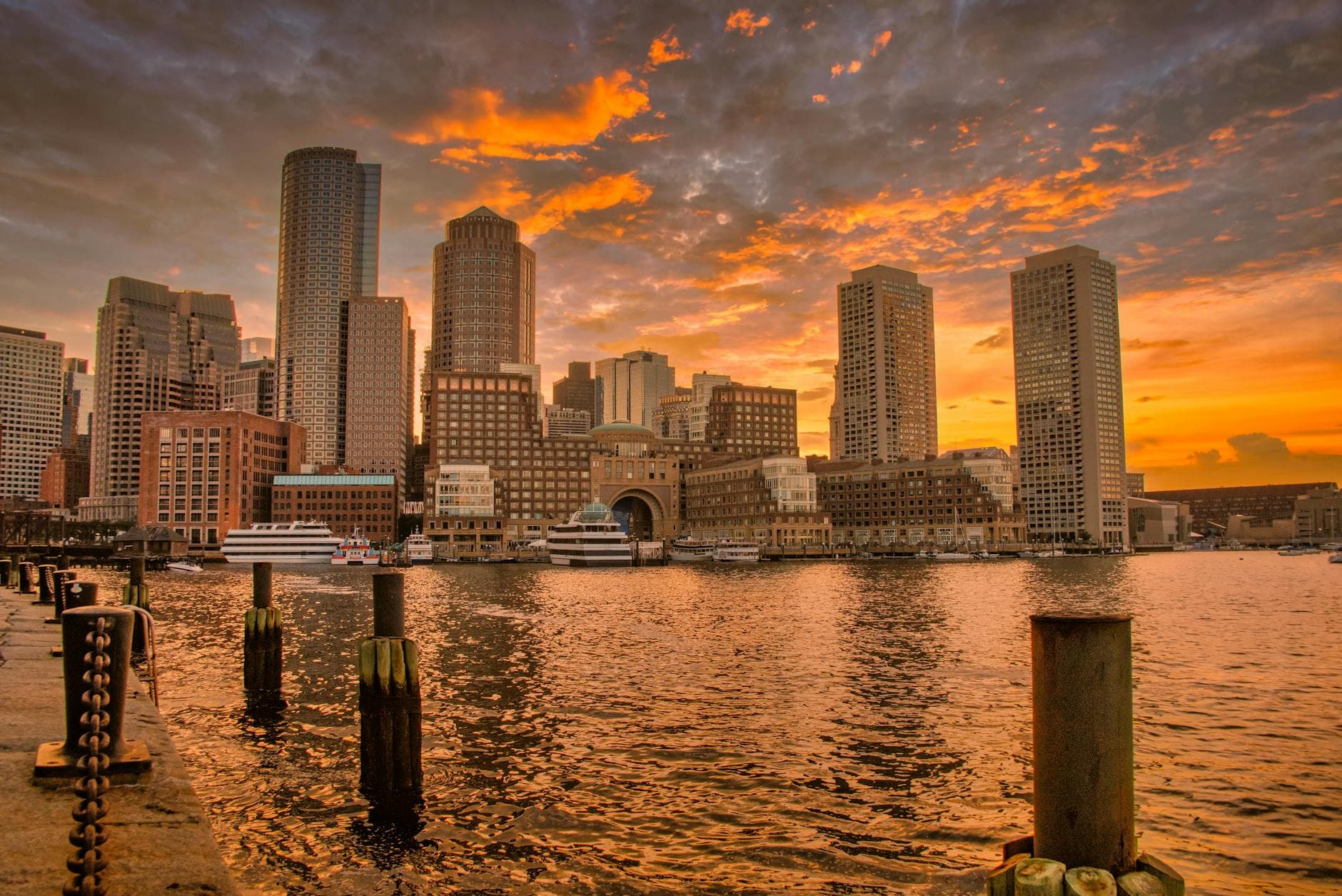 Stunning sunset over Boston's iconic skyline reflecting in the harbor waters.