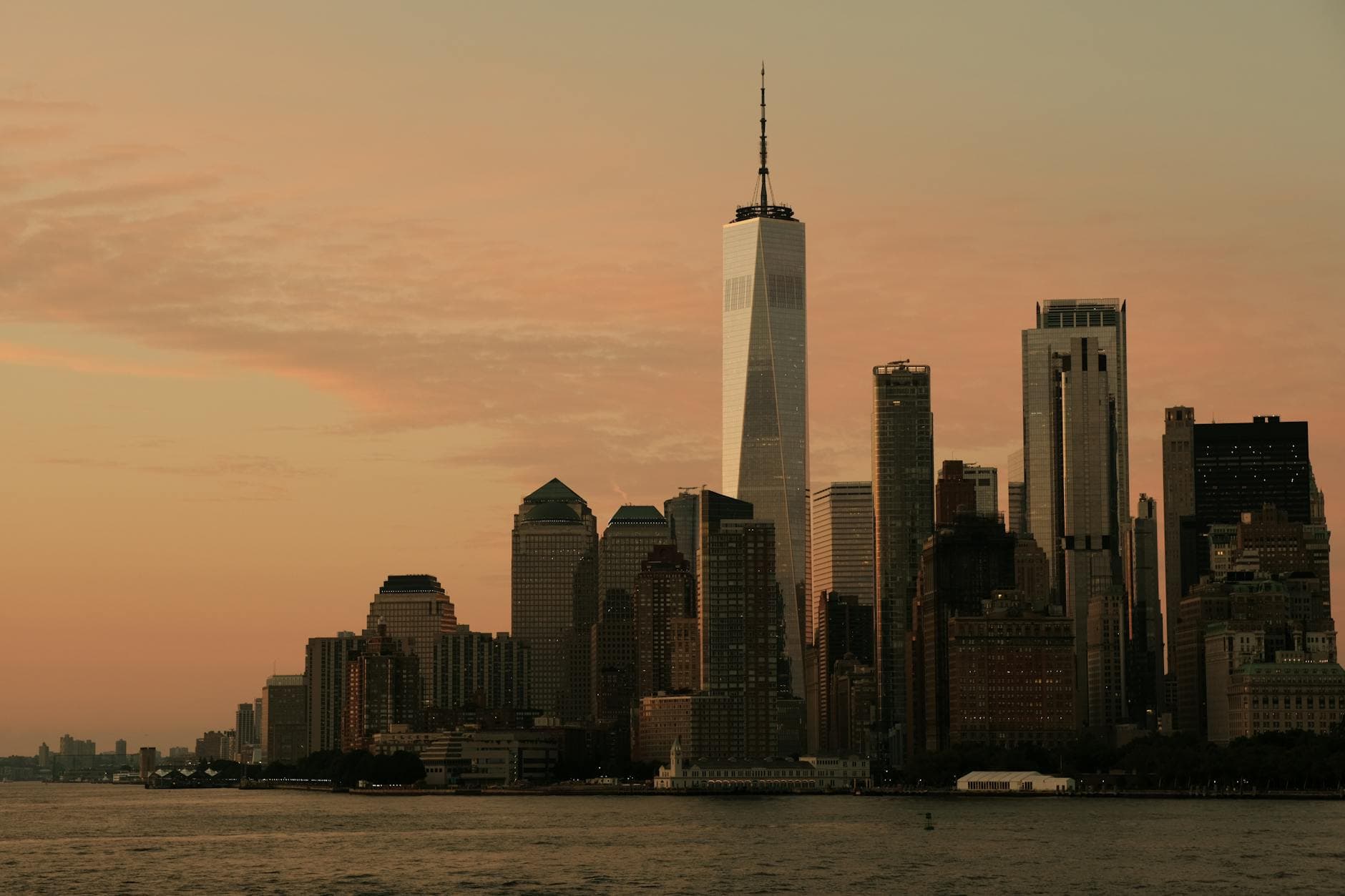 Dramatic sunset view of Lower Manhattan skyline featuring One World Trade Center in New York City.