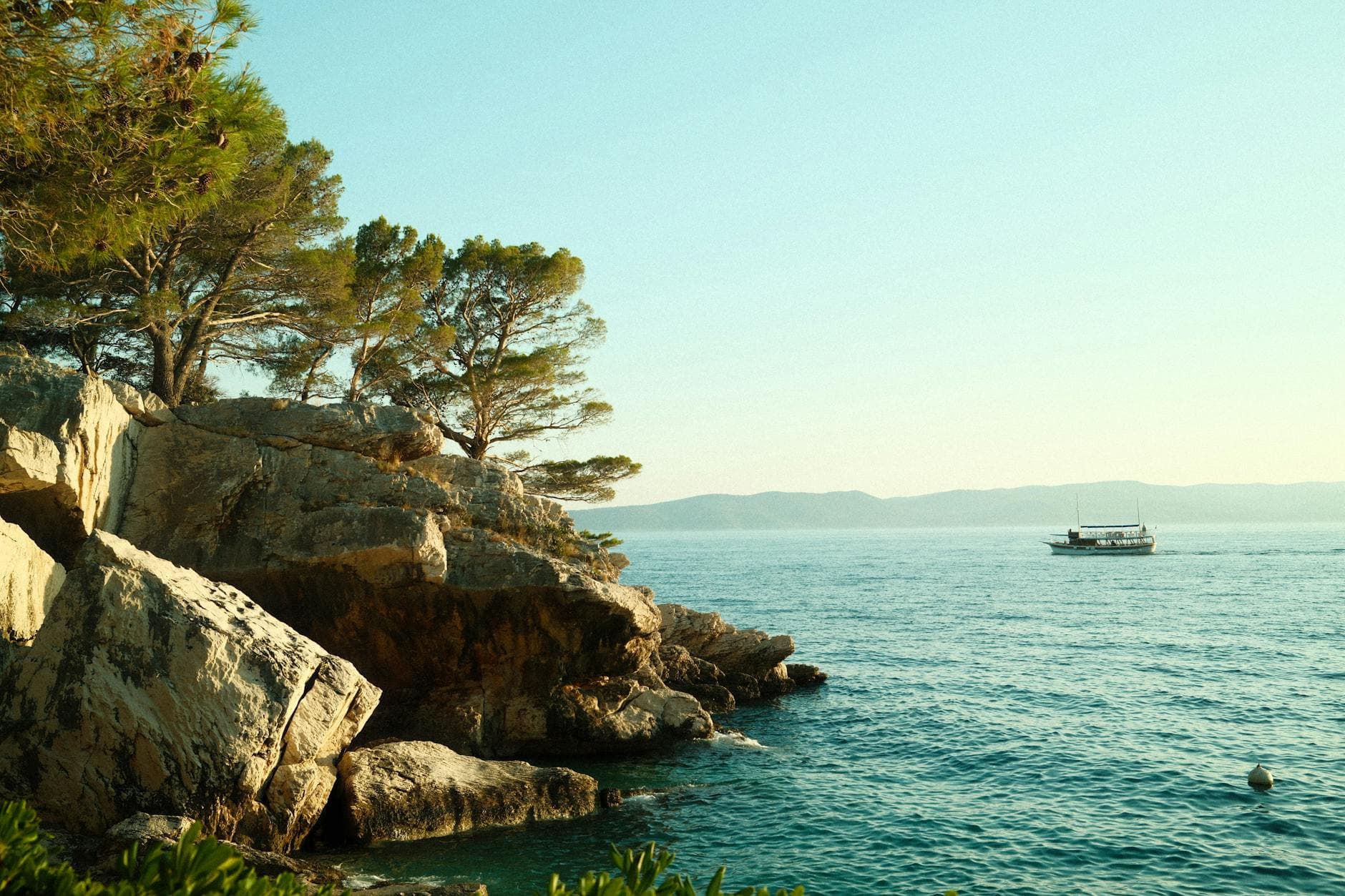 Serene view of the Adriatic Sea with rocky coastline and boat in Brela, Croatia.