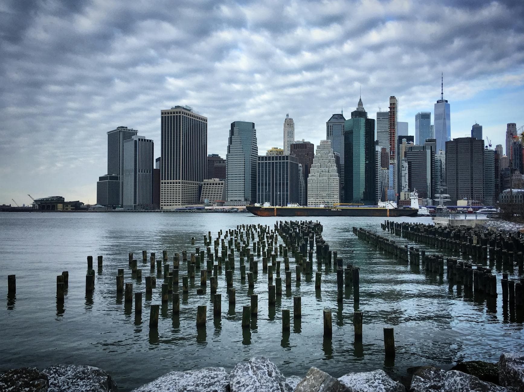 Stunning view of Manhattan skyline from Brooklyn waterfront with pilings in winter.