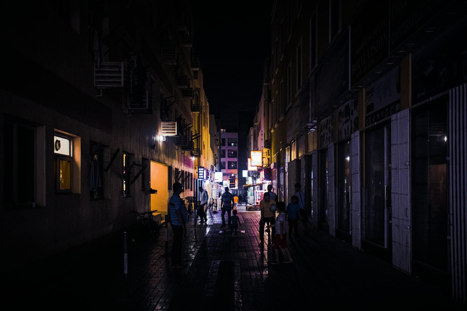 Explore the bustling night scene in Dubai's Bur Dubai with illuminated streets and silhouetted pedestrians.