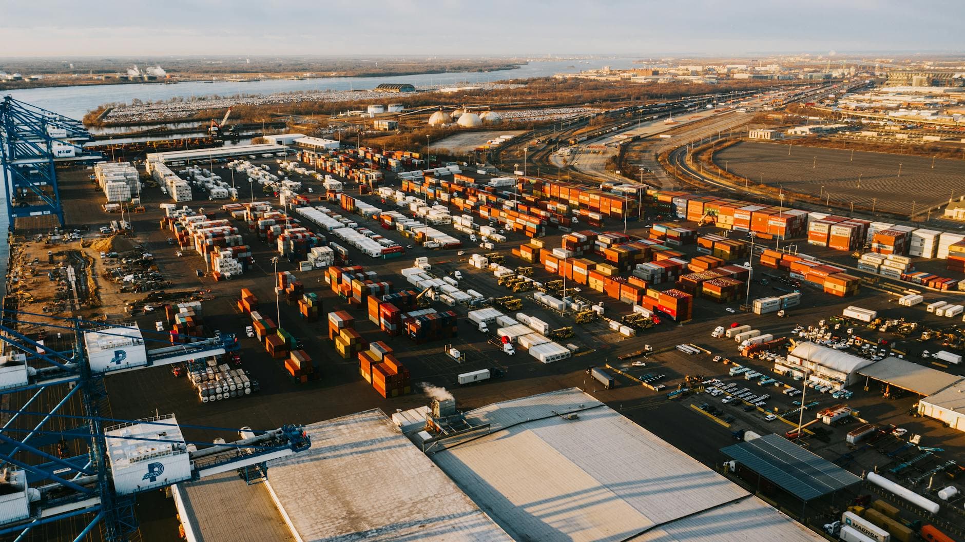 Aerial view of a busy shipping port in Philadelphia, showcasing containers and cranes.