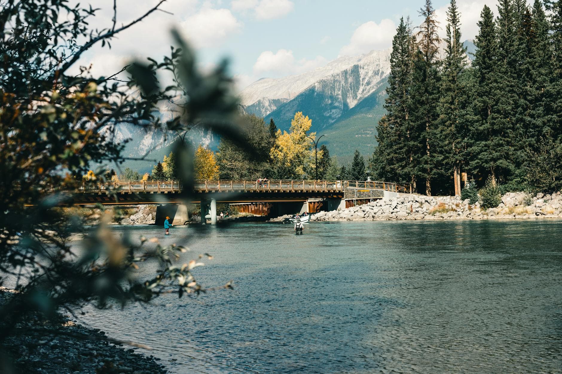 Picturesque view of a bridge over a river with a mountain backdrop in Canmore, Canada.