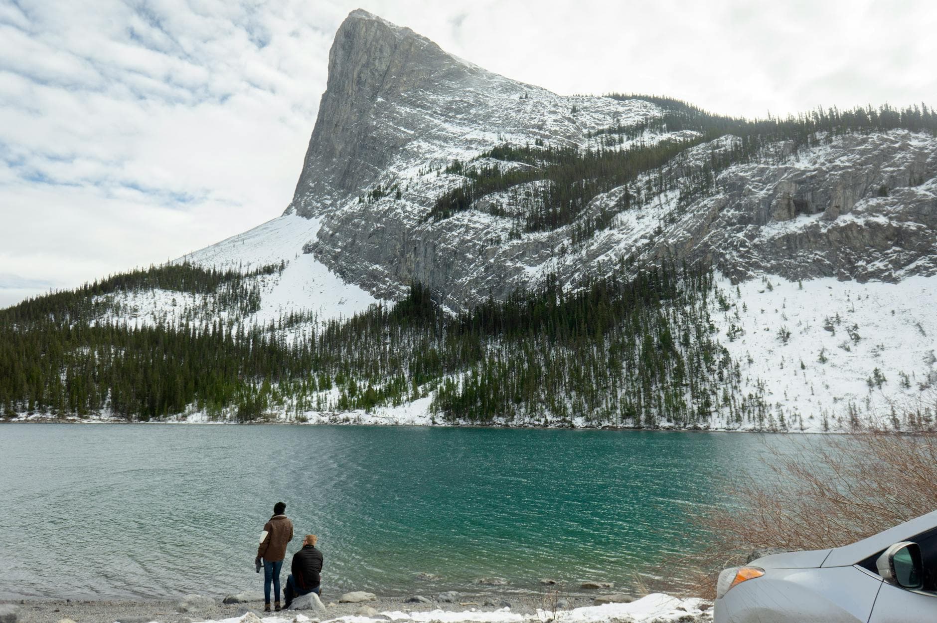 A couple enjoys the scenic winter mountain view by the lake in Canmore, Alberta, Canada.