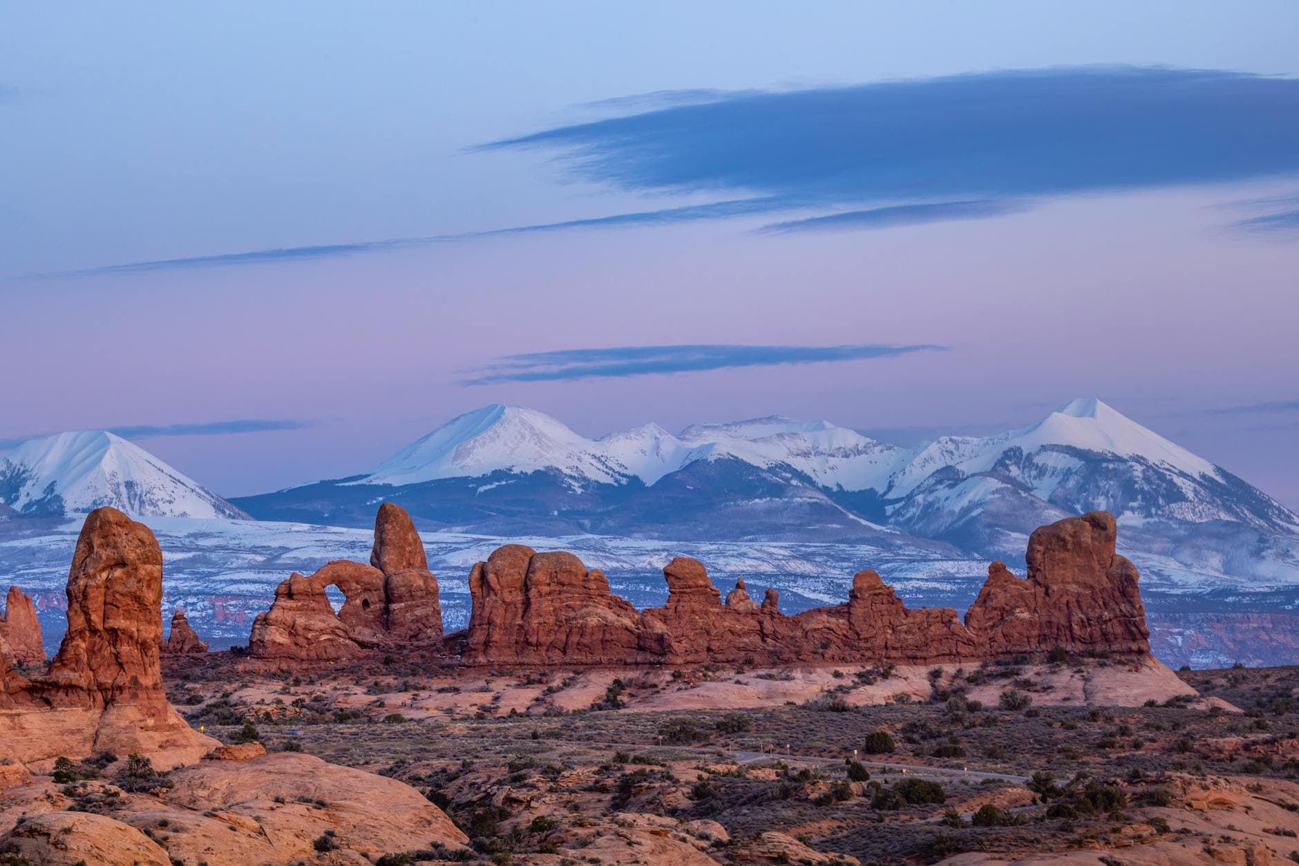 Stunning view of Arches National Park at dusk with snowcapped mountains in Utah.