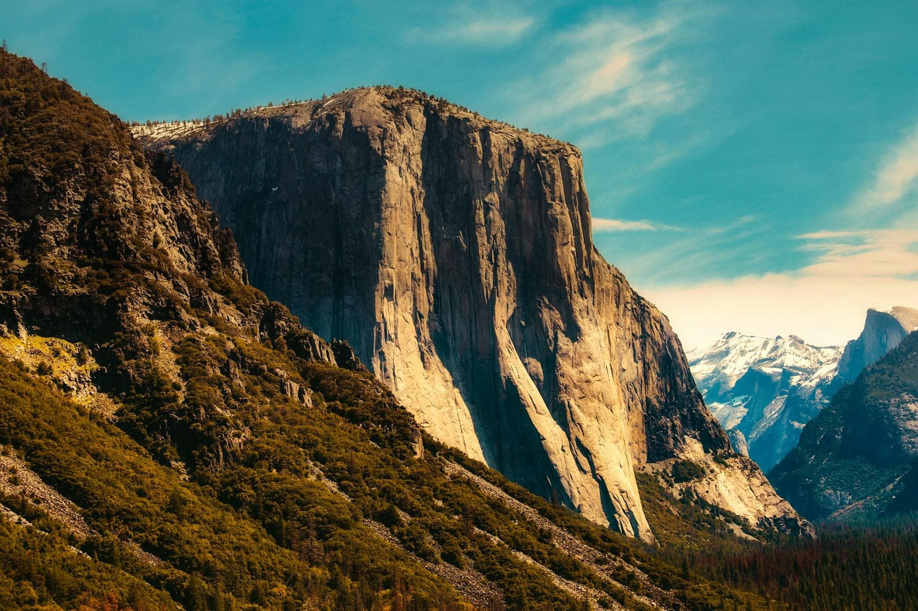 Stunning view of El Capitan rock formation in Yosemite with mountains and clear sky.