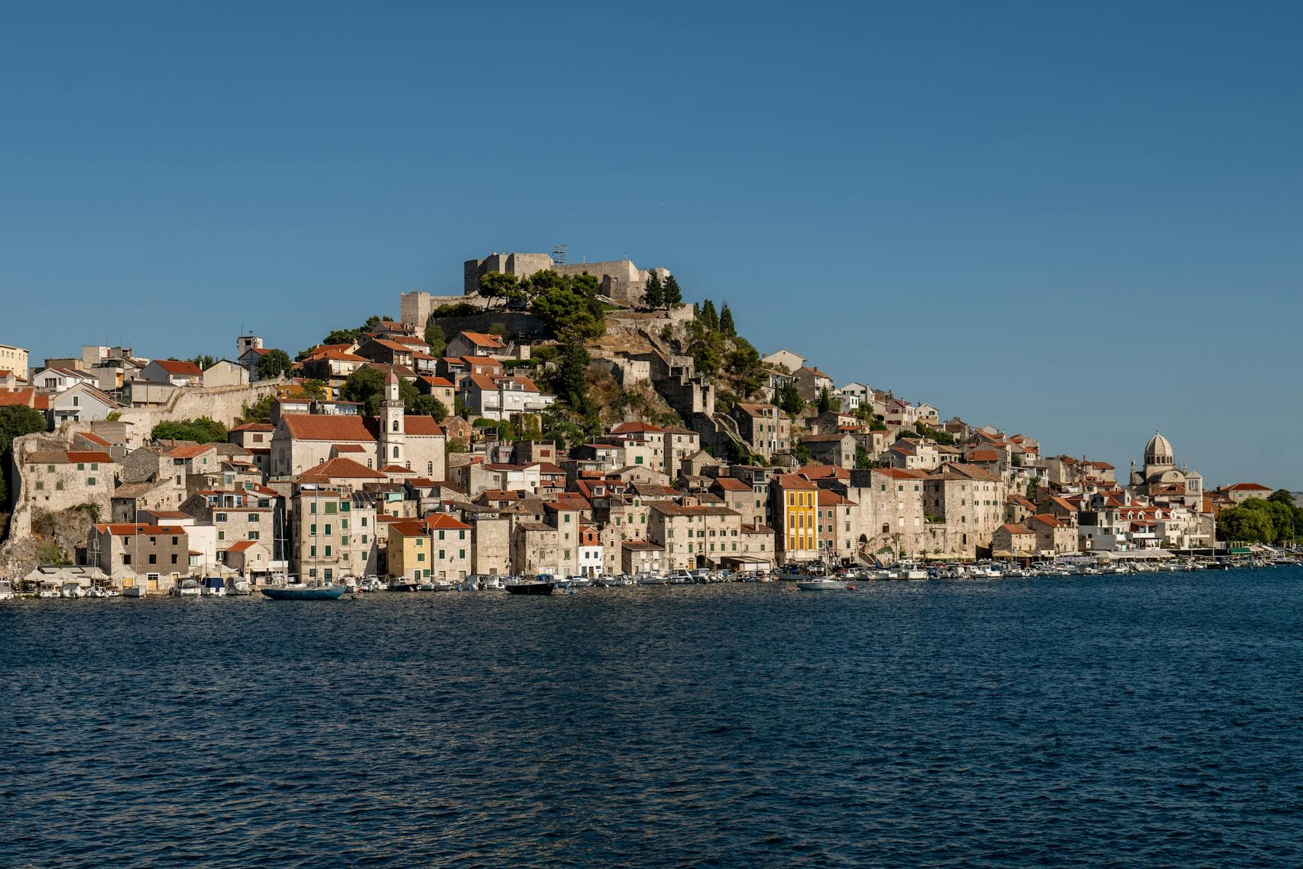 Stunning view of Šibenik's coastline featuring Saint Michael's Fortress under a clear blue sky.