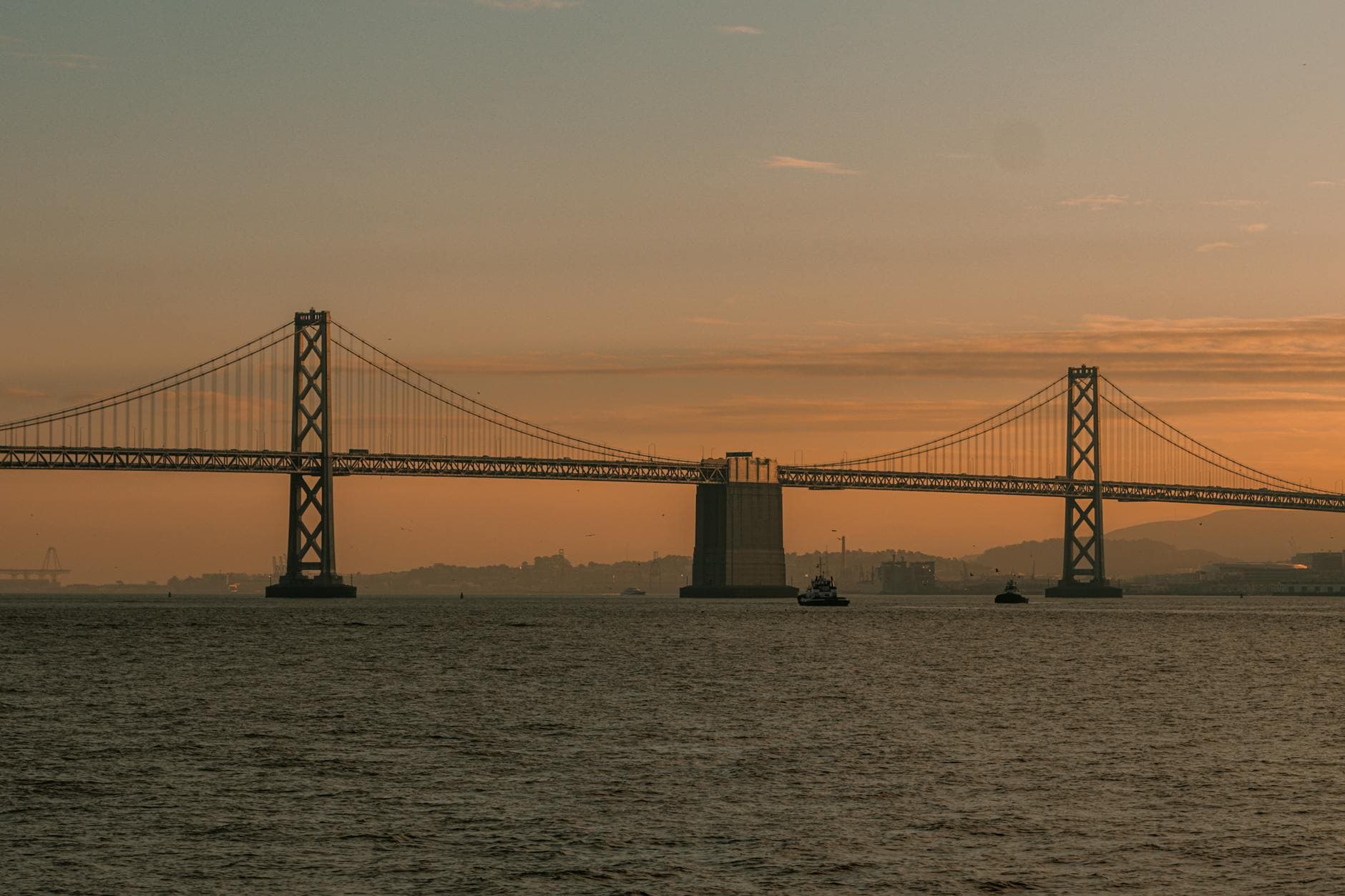 Silhouette of Bay Bridge at sunset over San Francisco Bay, creating a serene and picturesque view.