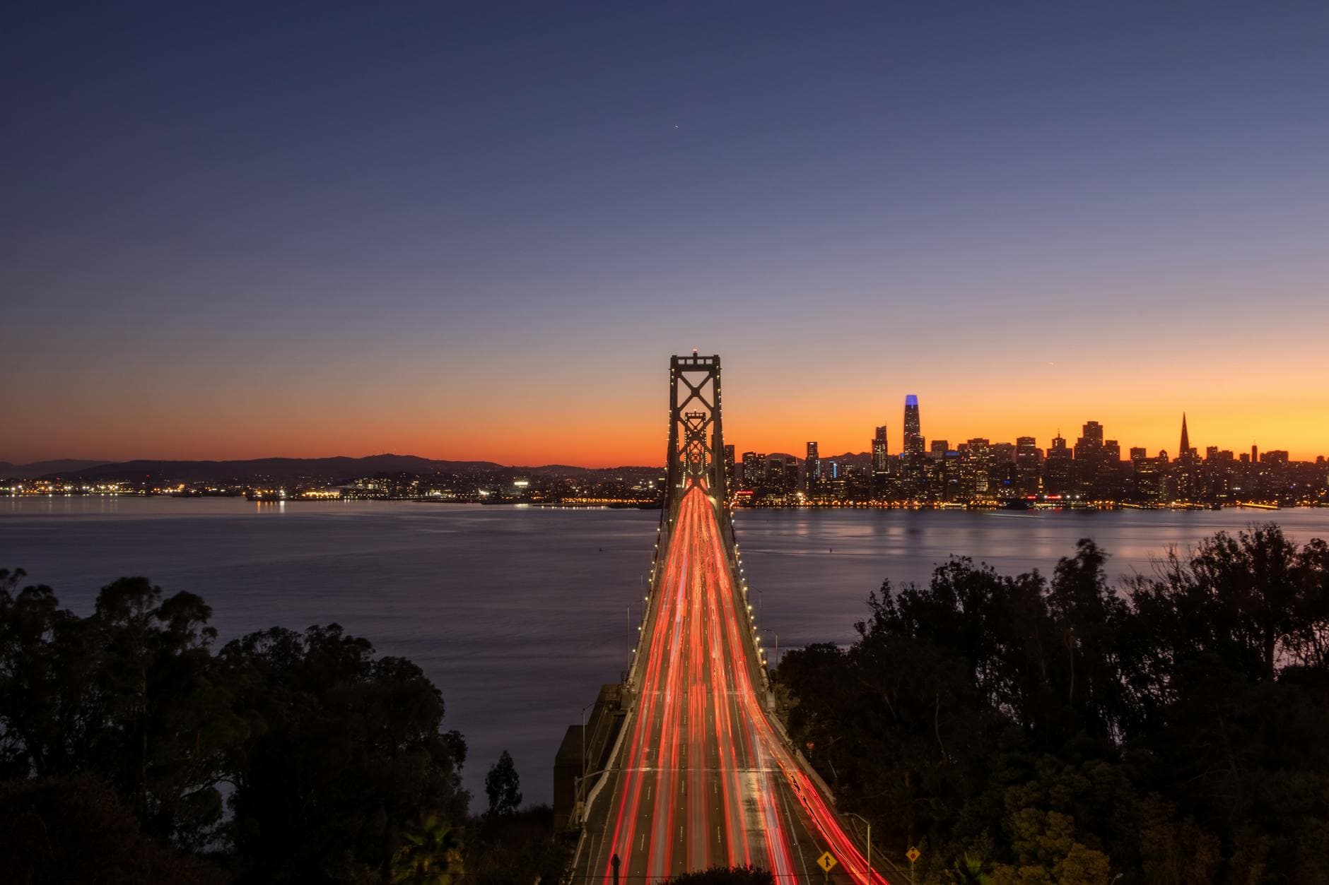 Stunning long exposure of the Bay Bridge in San Francisco at twilight with the skyline in view.