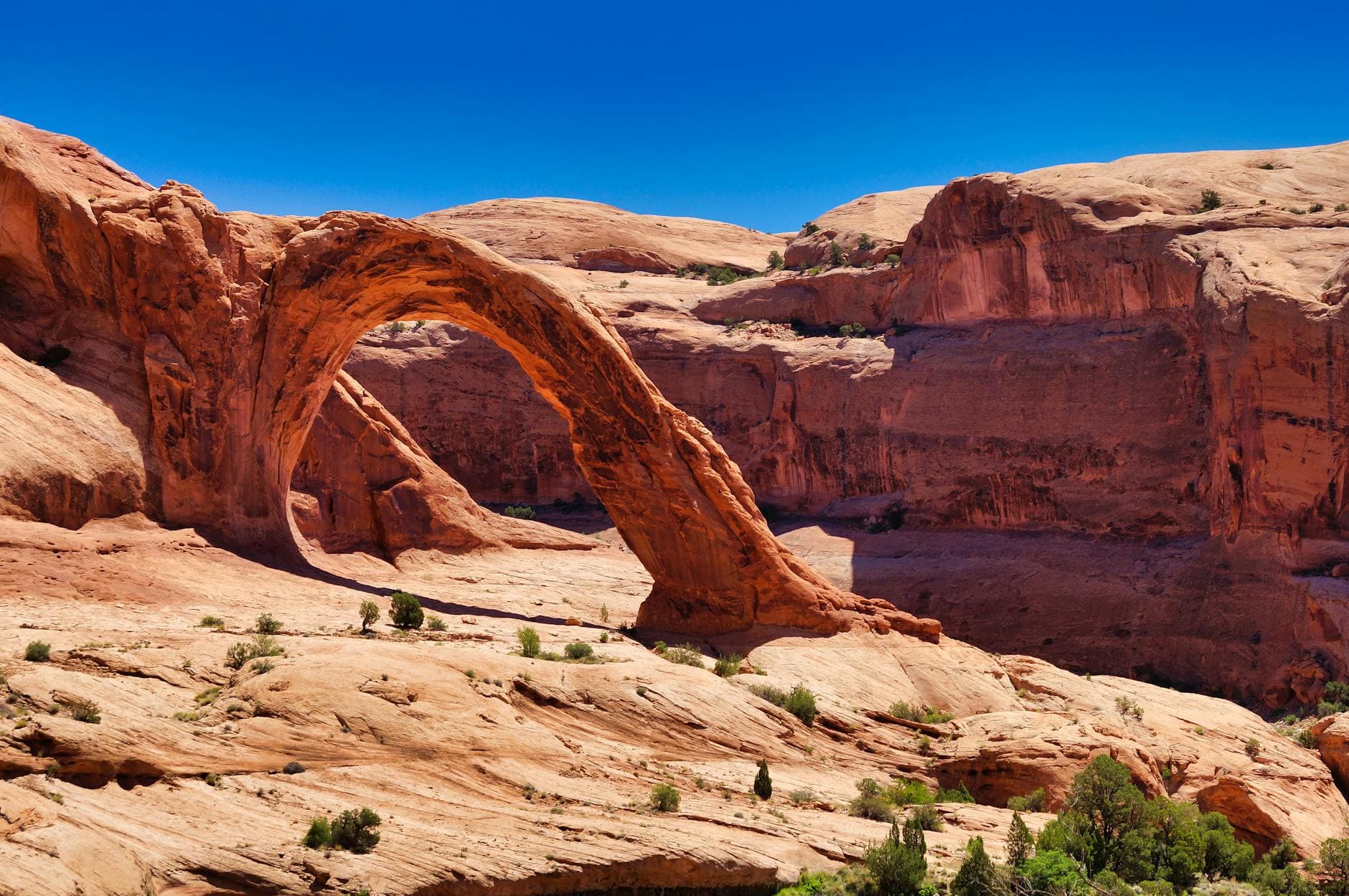 Stunning view of Corona Arch, a natural rock formation in Moab, Utah, under a clear blue sky.