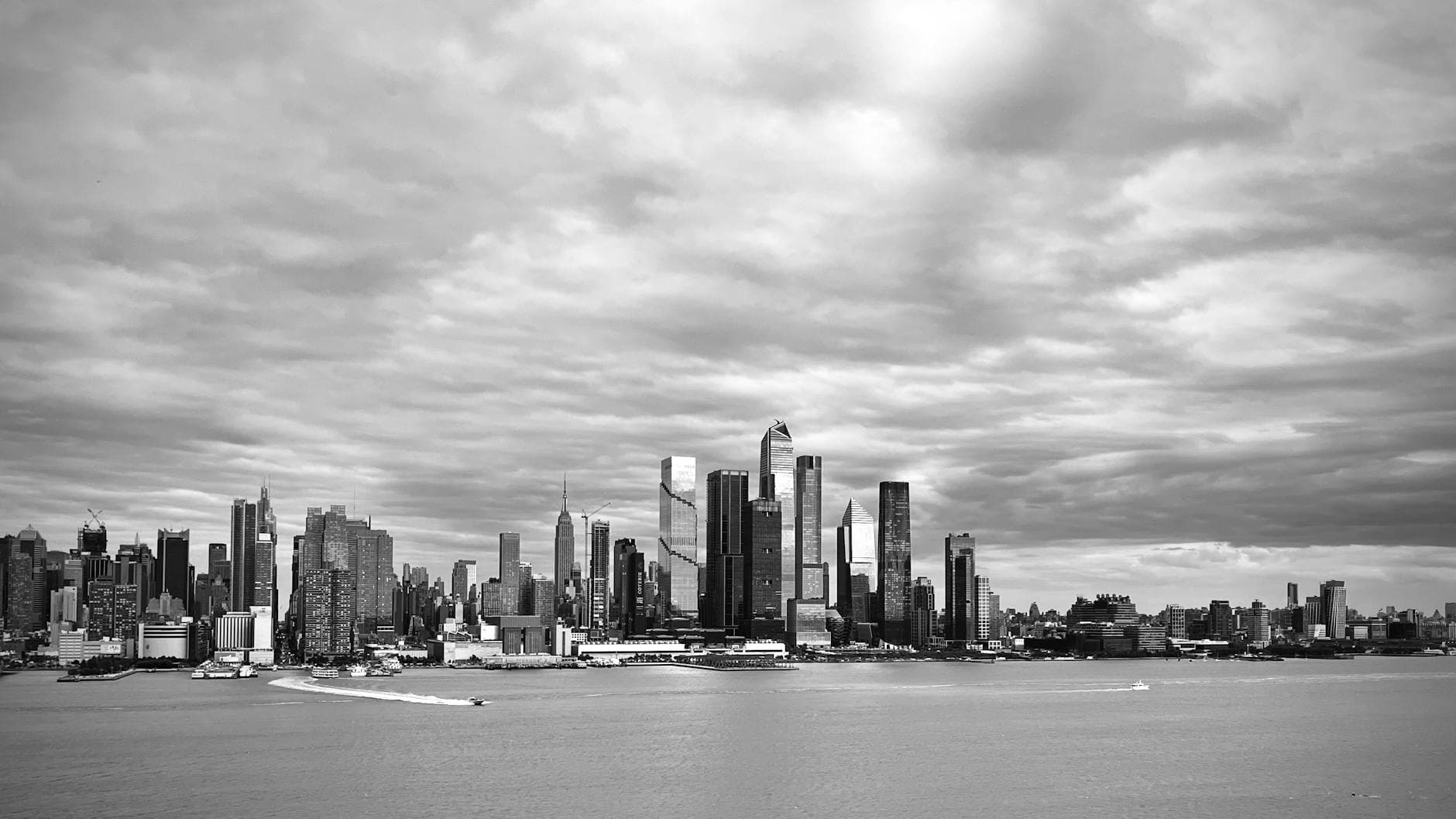 Panoramic black and white view of New York City's modern skyline over the waterfront.