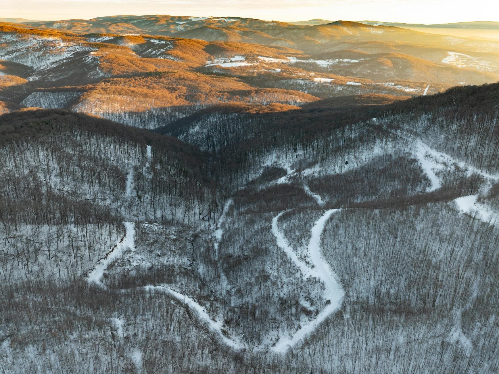 Aerial view of snow-covered hills and winding paths in Daruvar, Croatia during winter.