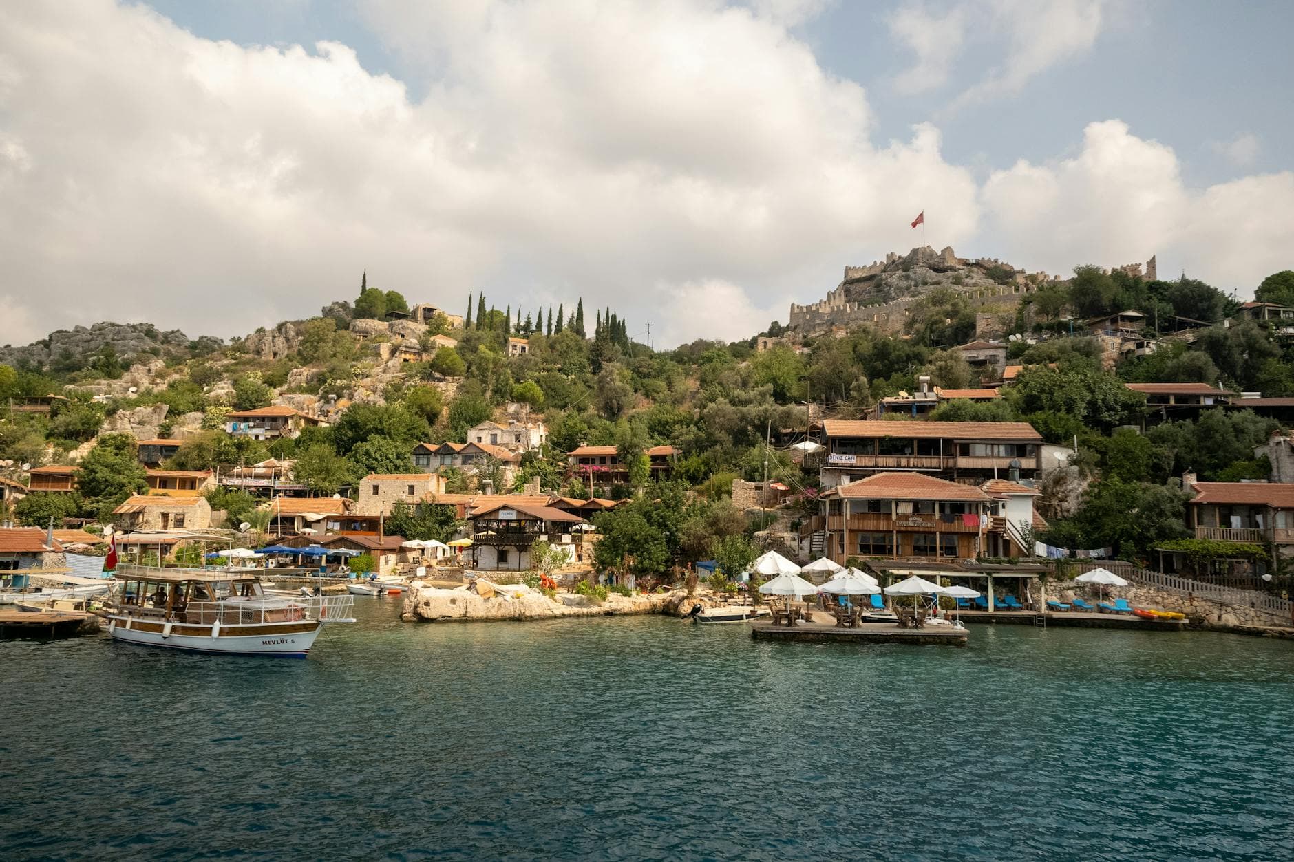 Explore the picturesque waterfront of Kaleköy in Turkey with boats and historic buildings.