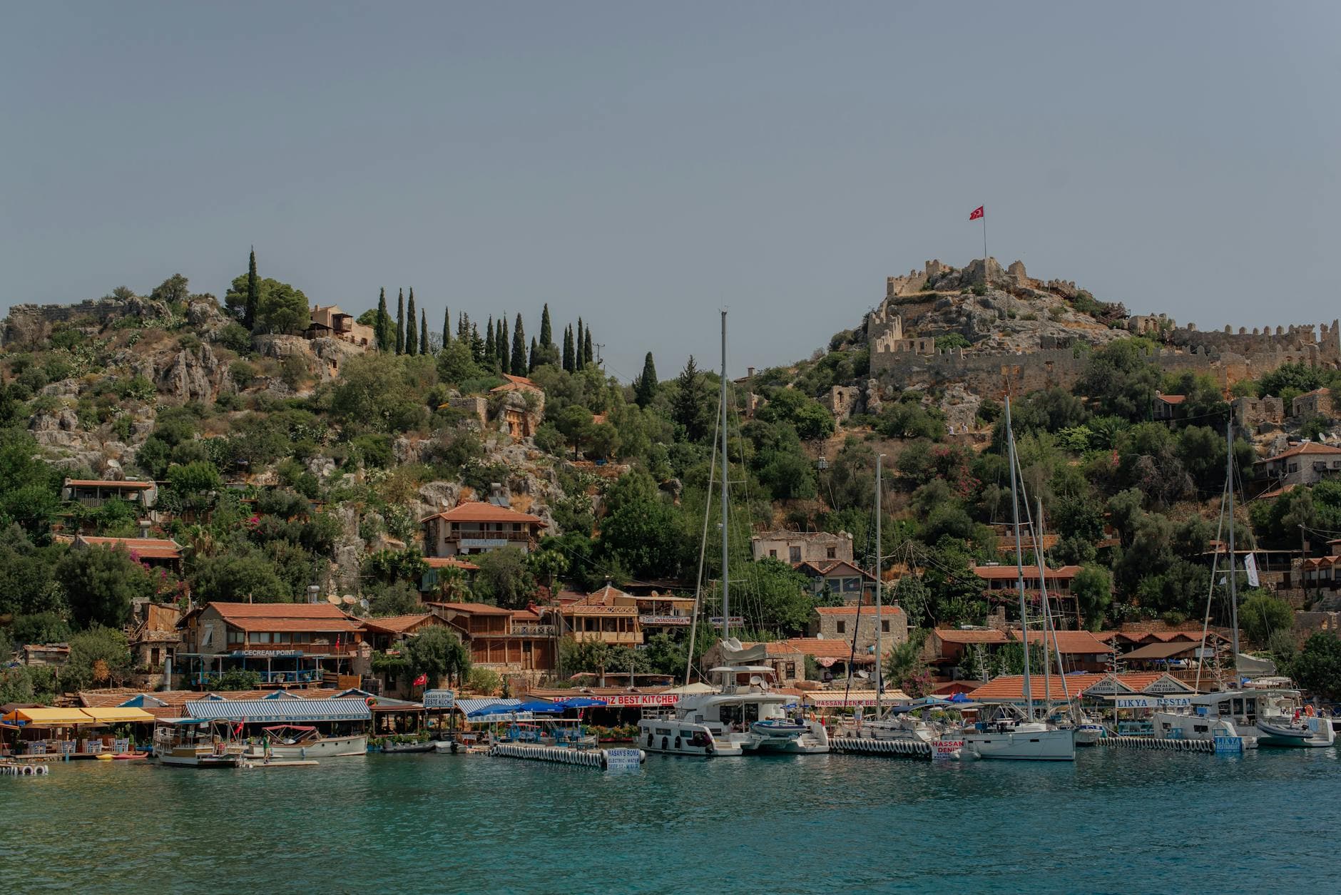 Picturesque harbor at Kekova with boats and historic hillside overlooking the Mediterranean Sea.