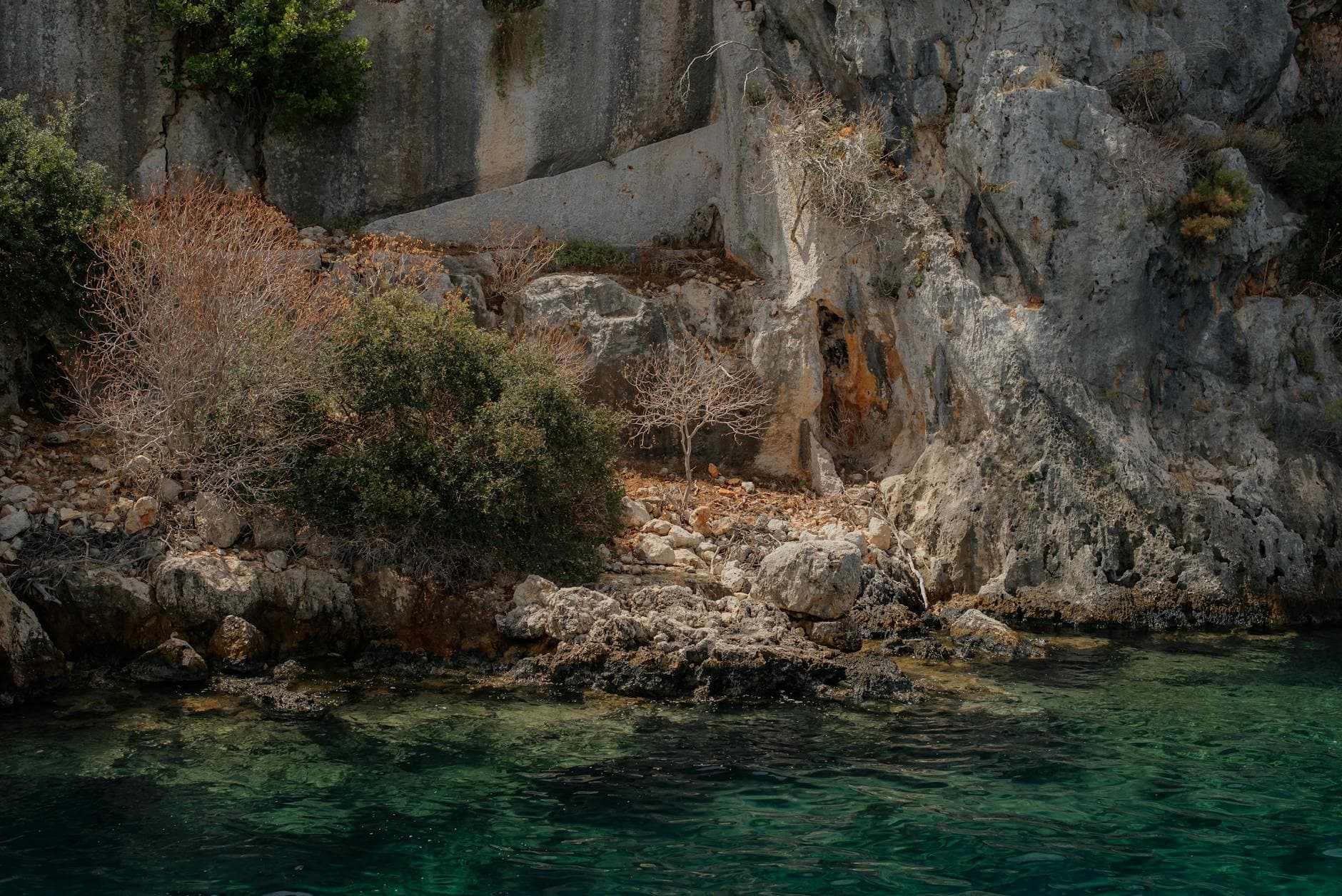 Stunning rocky shoreline in Demre, Turkey featuring clear turquoise waters and ancient stone formations.