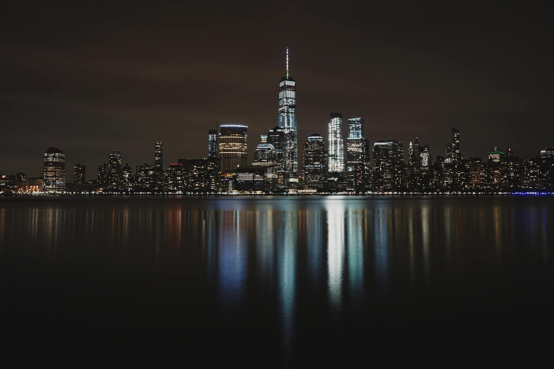 Captivating night view of the New York City skyline, beautifully reflected on the waterfront, showcasing urban architecture.