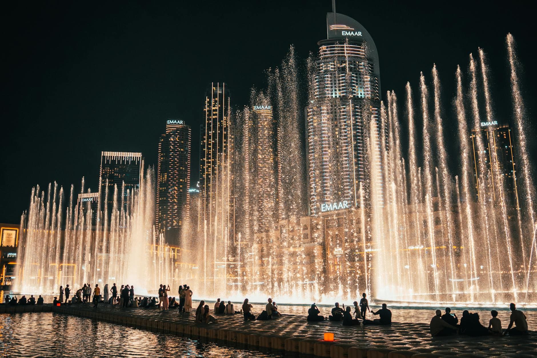 A breathtaking night view of the Dubai Fountain with city skyscrapers in the background.