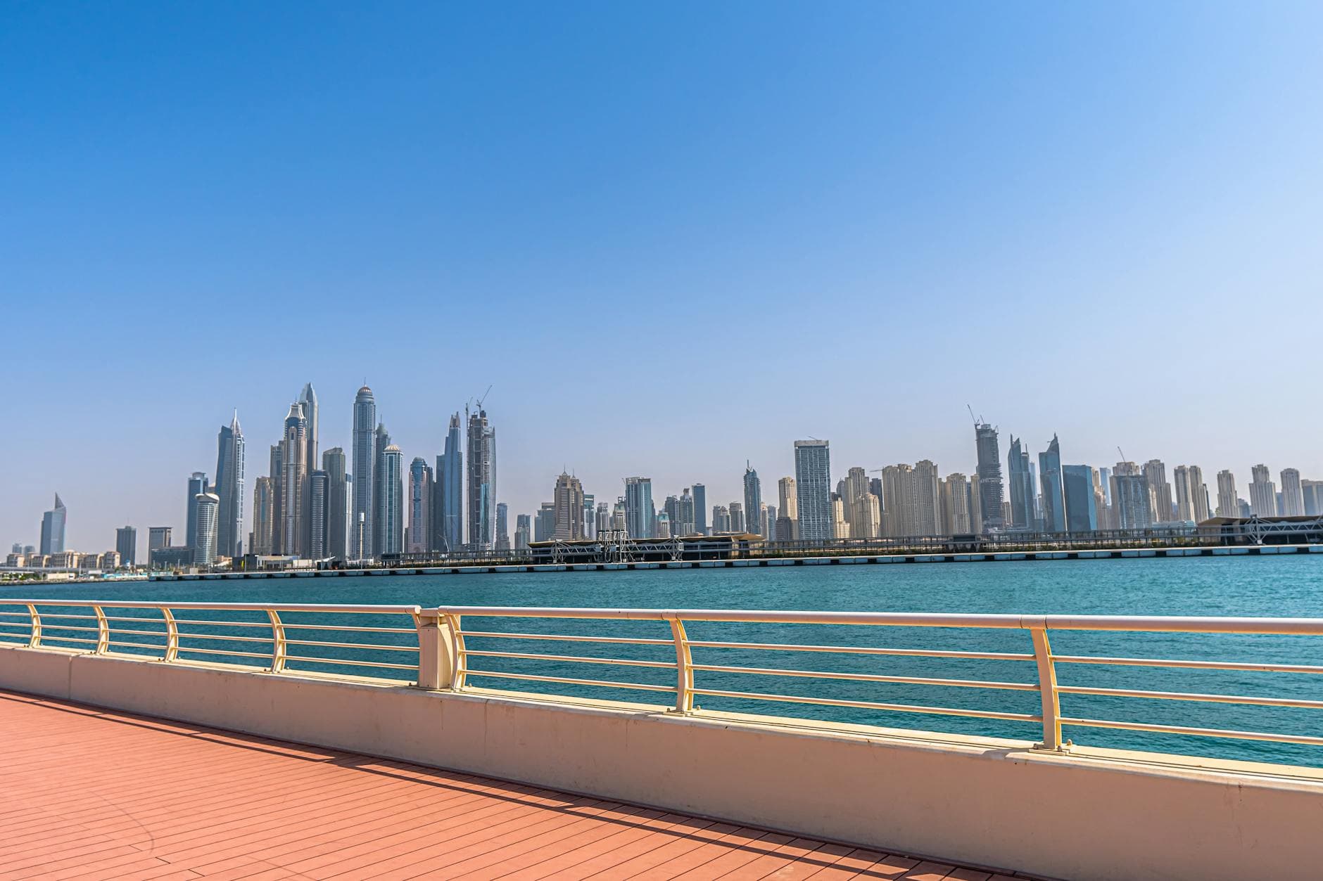 Beautiful view of Dubai Marina skyline and waterfront under a clear blue sky, showcasing urban architecture.