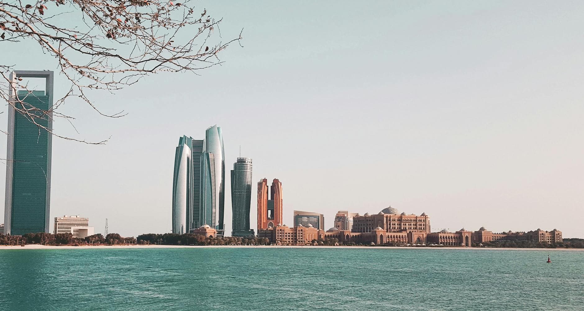 A beautiful view of Abu Dhabi's skyline featuring the iconic Etihad Towers and waterfront buildings during the day.