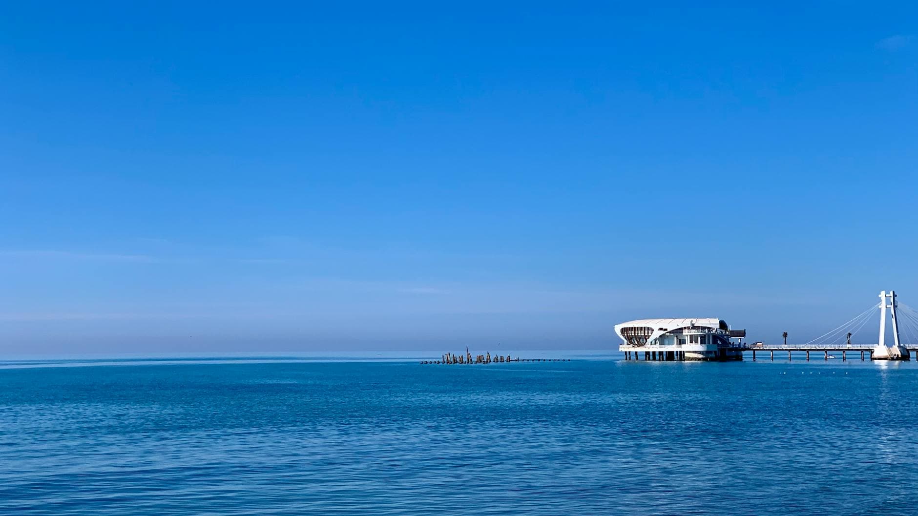 Scenic sea view of a pier stretching into the Adriatic Sea in Durrës, Albania under a clear blue sky.