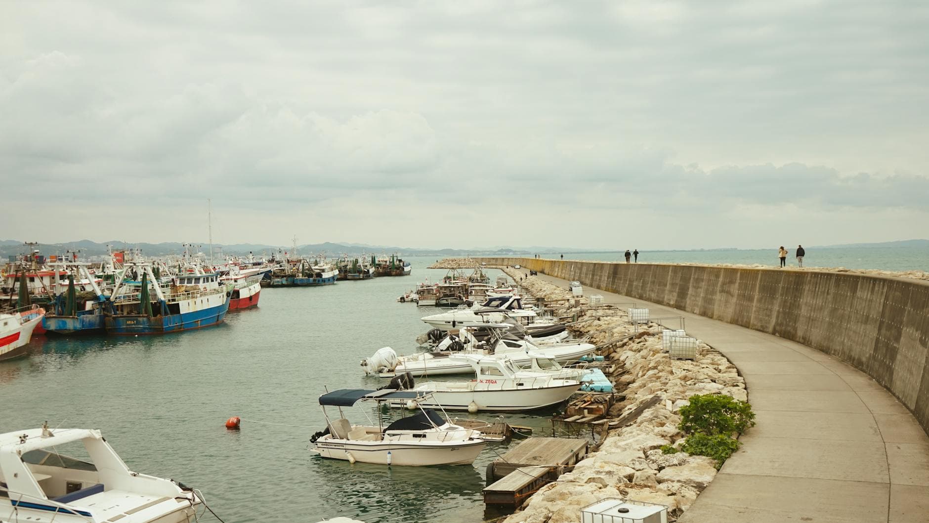 Peaceful marina in Durrës, Albania with boats docked along a stone pathway.