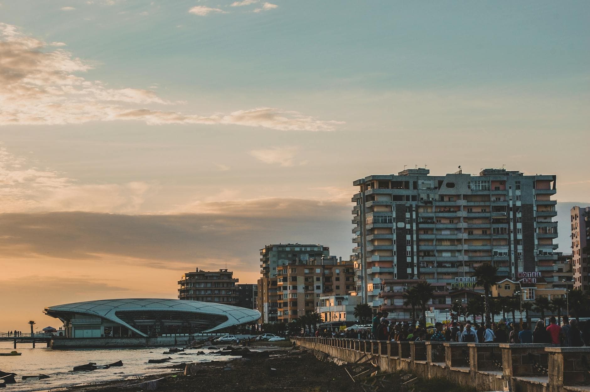 Scenic view of Durrës coastline at sunset featuring modern buildings and a vibrant promenade.