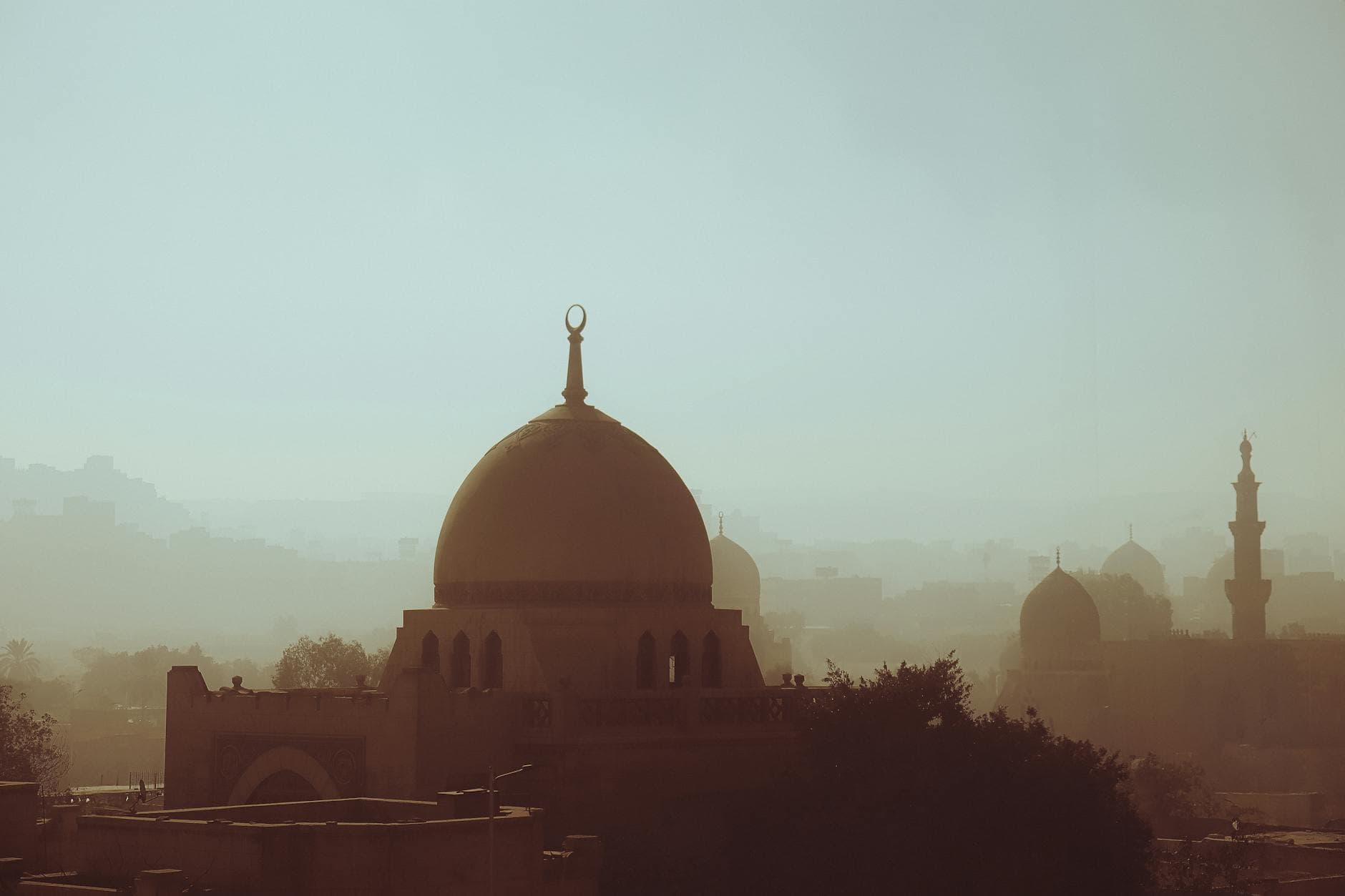Serene view of Cairo's skyline silhouetted in mist, highlighting ancient Islamic architecture.
