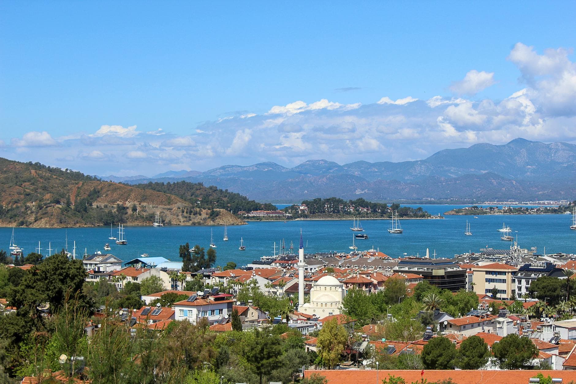 Scenic aerial view of Fethiye with its bay, harbor, and mountains under a clear sky.